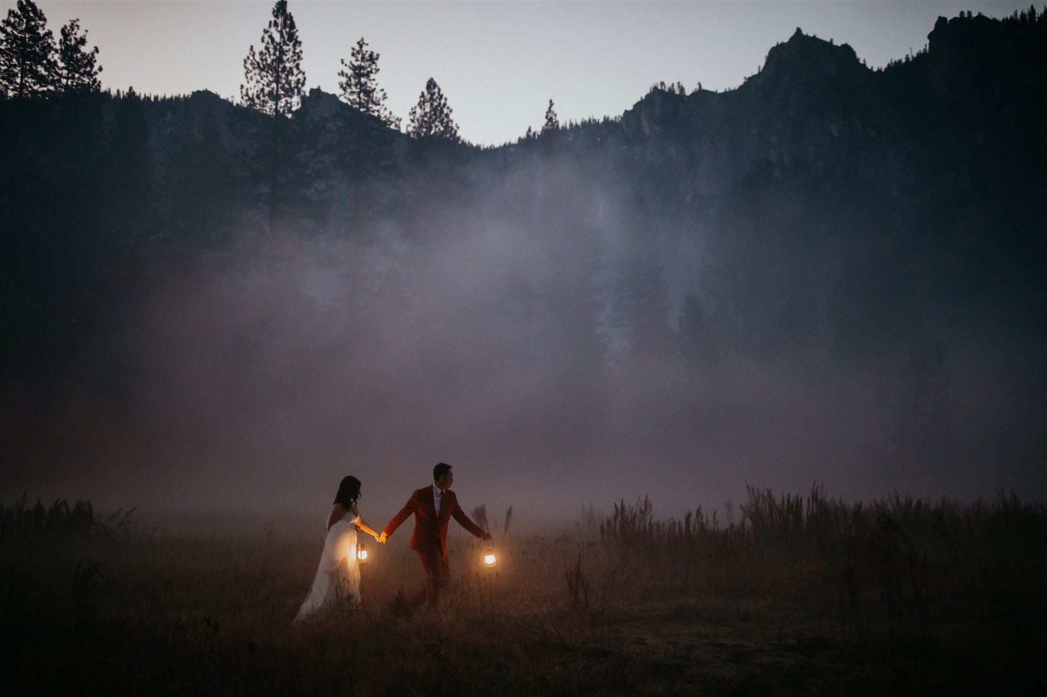 Bride and groom walking through El Capitan Meadow with lanterns for Yosemite Elopement
