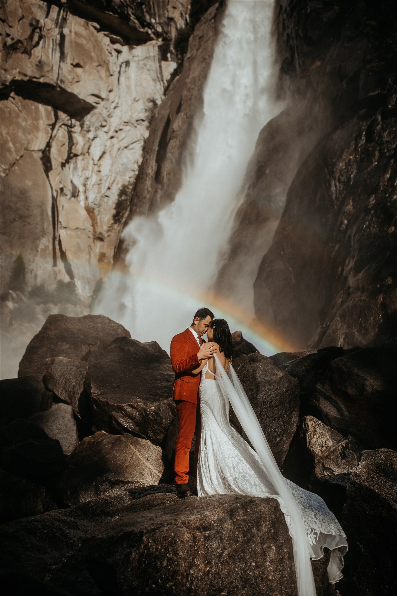 Bride and groom kissing under a waterfall for Yosemite elopement