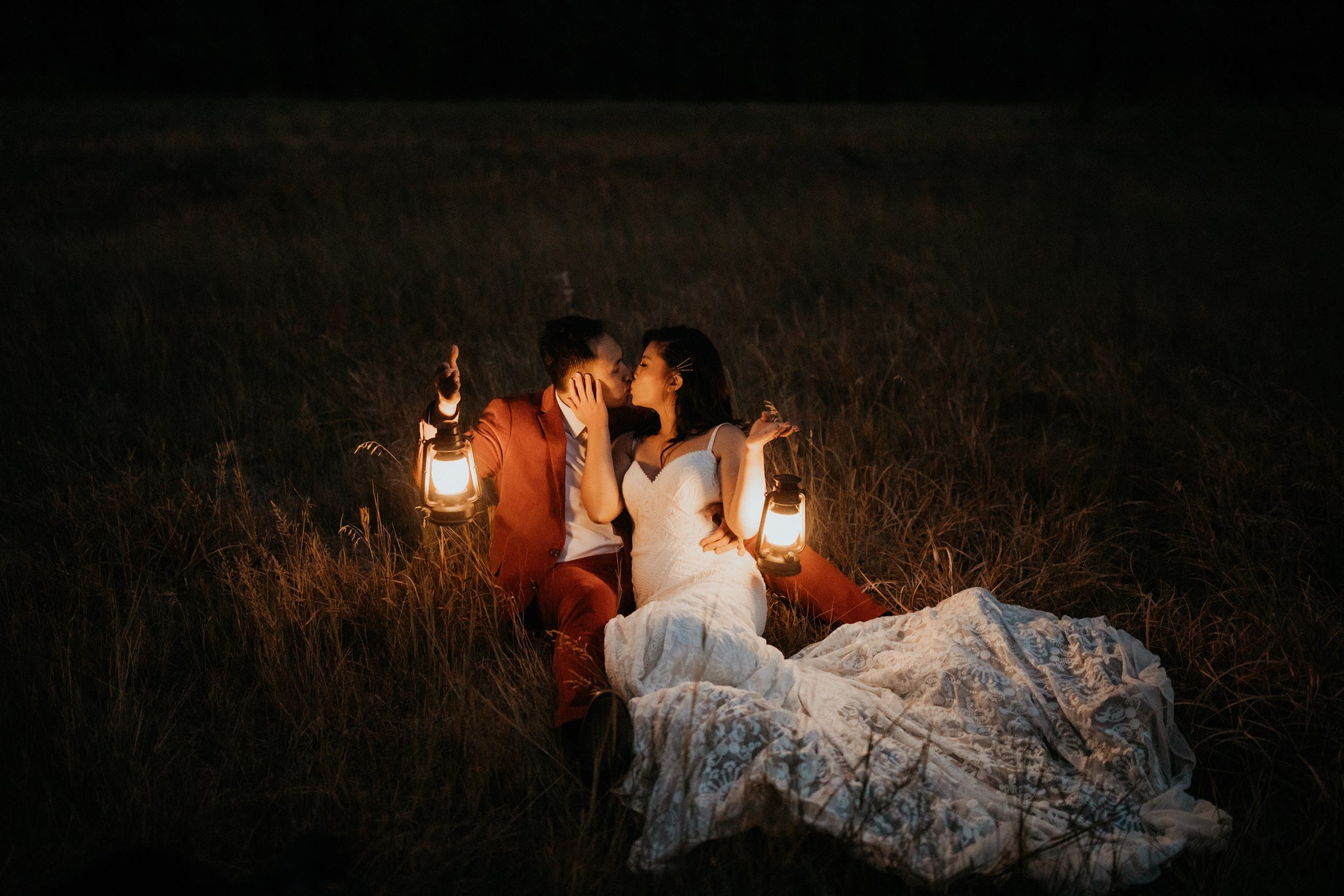 Bride and groom kissing while holding lanterns in El Capitan Meadow at Yosemite elopement