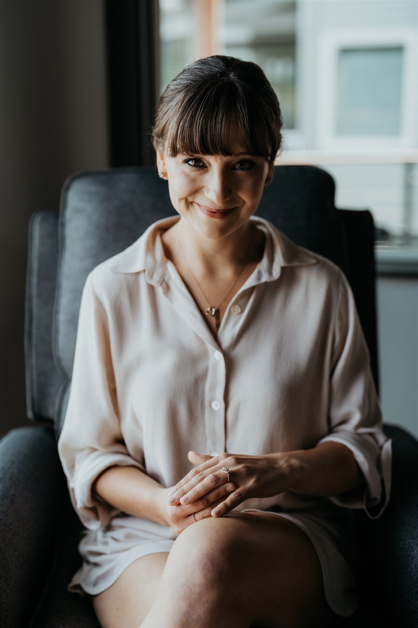 Bride sitting in oversized button down while getting ready for wedding day