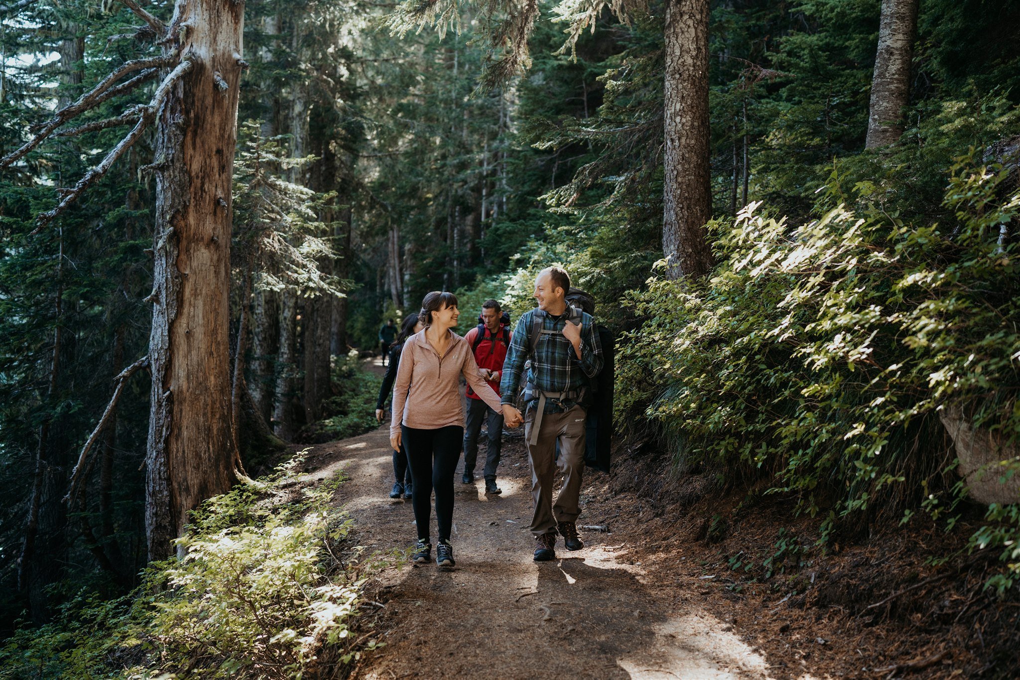 Bride and groom walking hand in hand down hiking trail