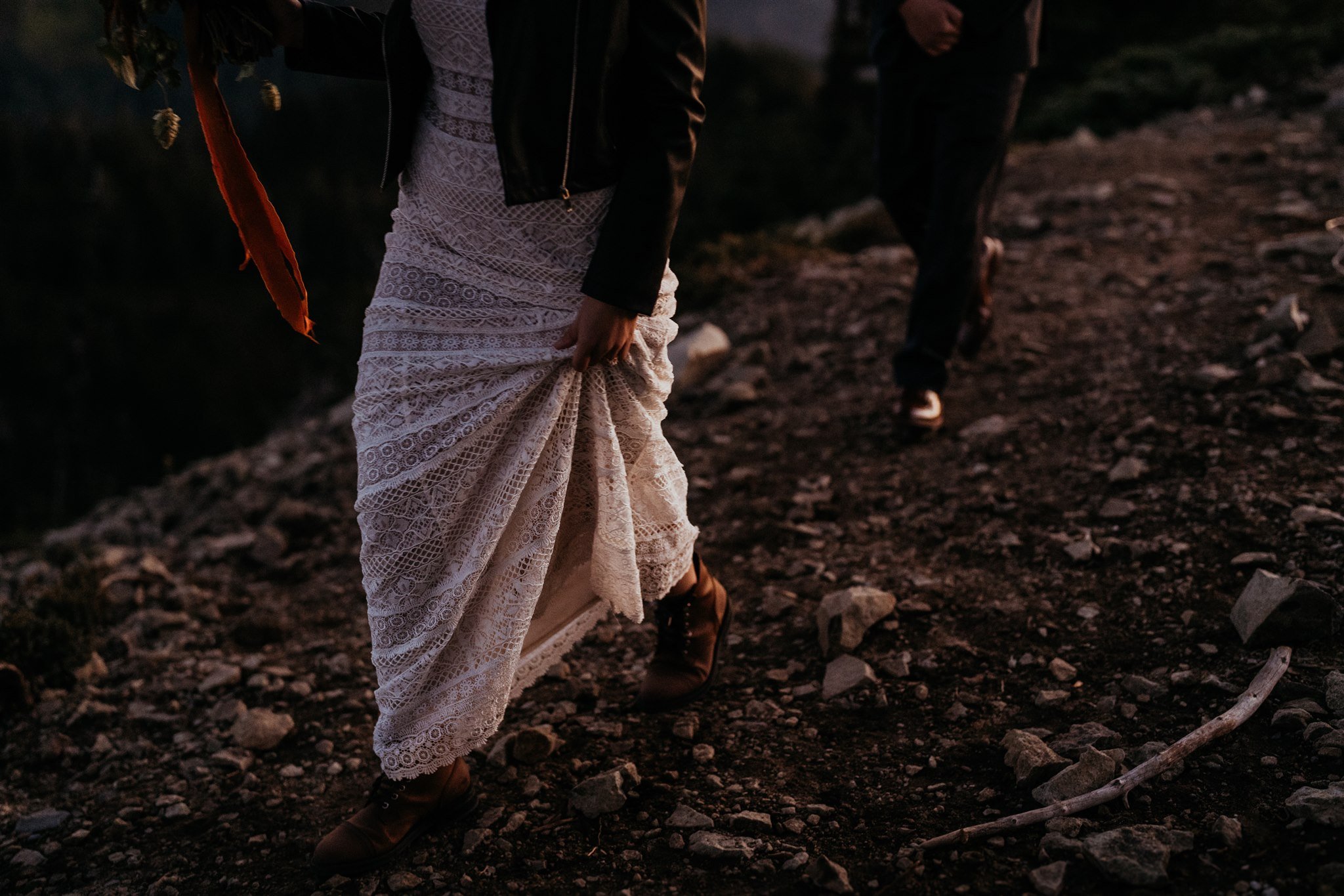 Bride and groom walk along hiking trail at sunset in Mt Rainier