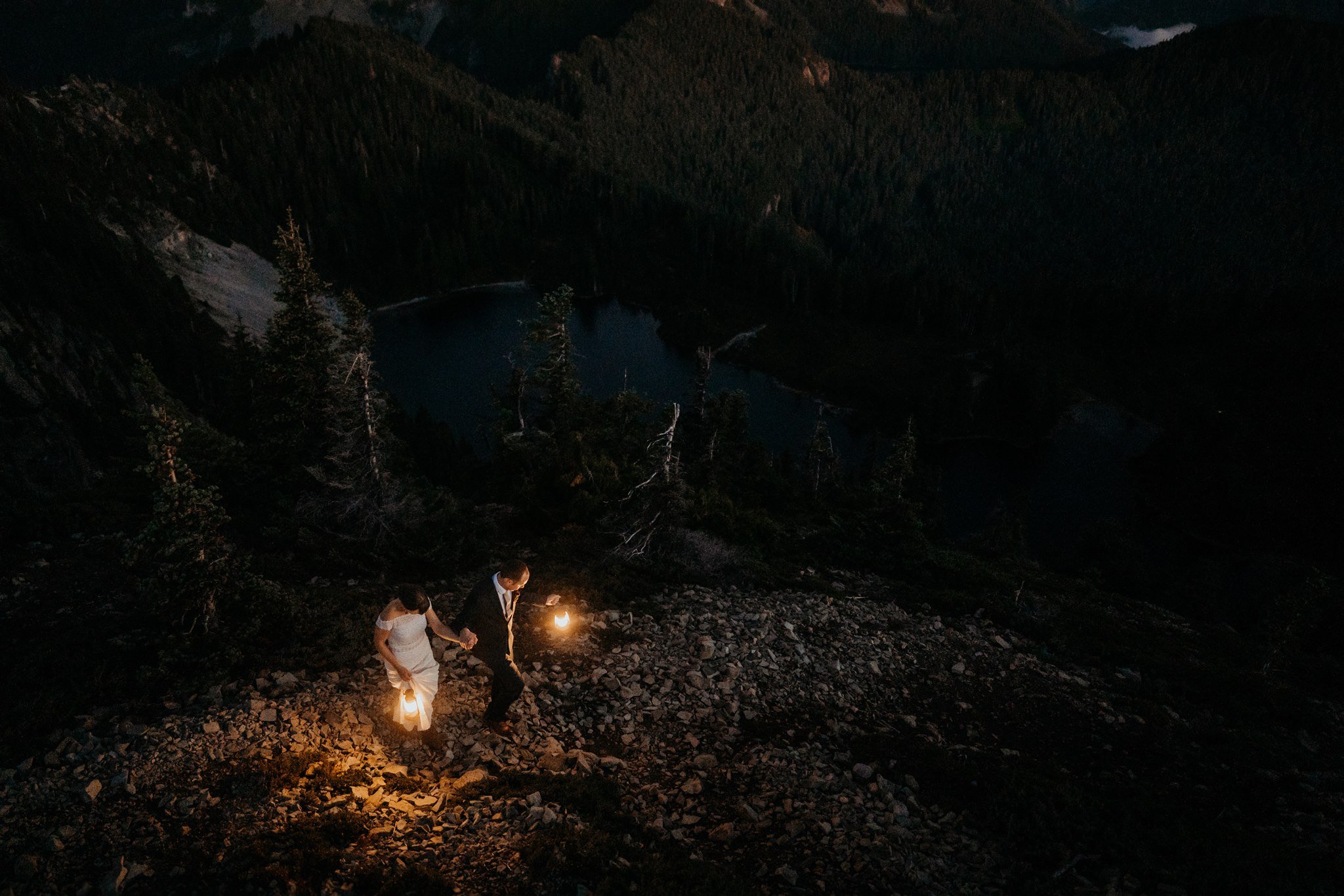 Bride and groom holding lanterns and hiking a trail at fall wedding in Rainier
