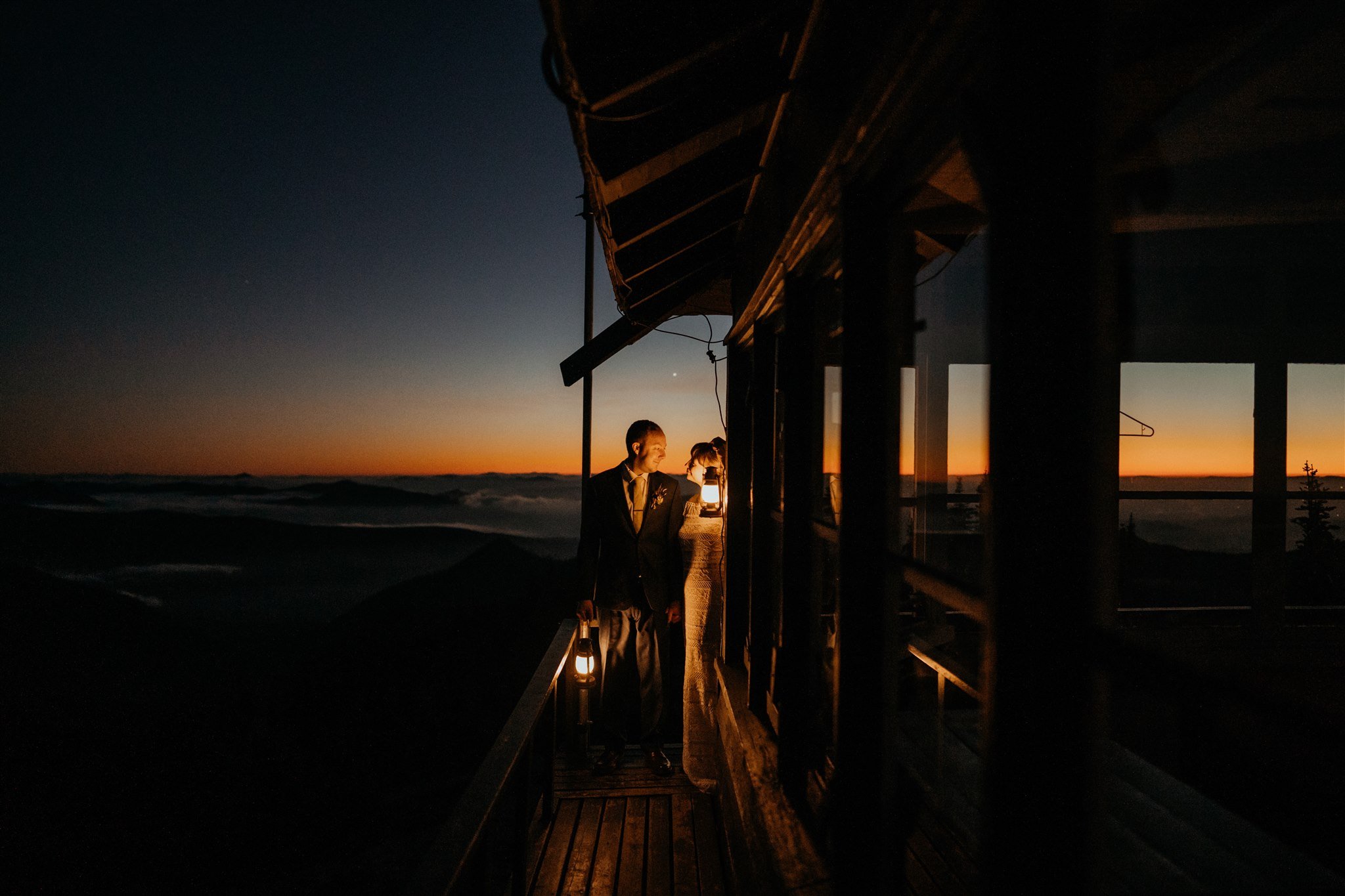 Bride and groom holding lanterns in fire lookout at Mt Rainier