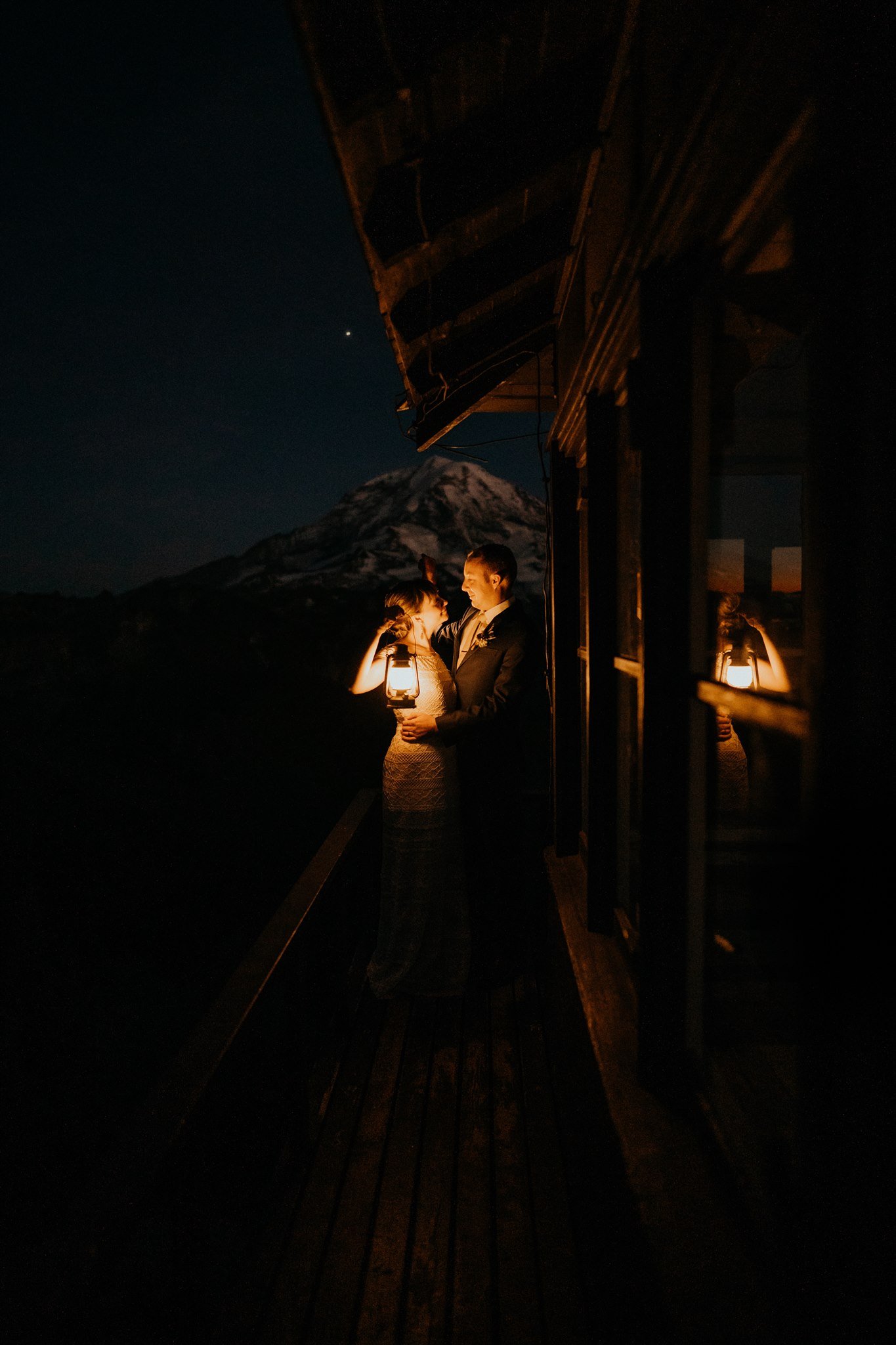 Bride and groom holding lanterns in fire lookout at Mount Rainier