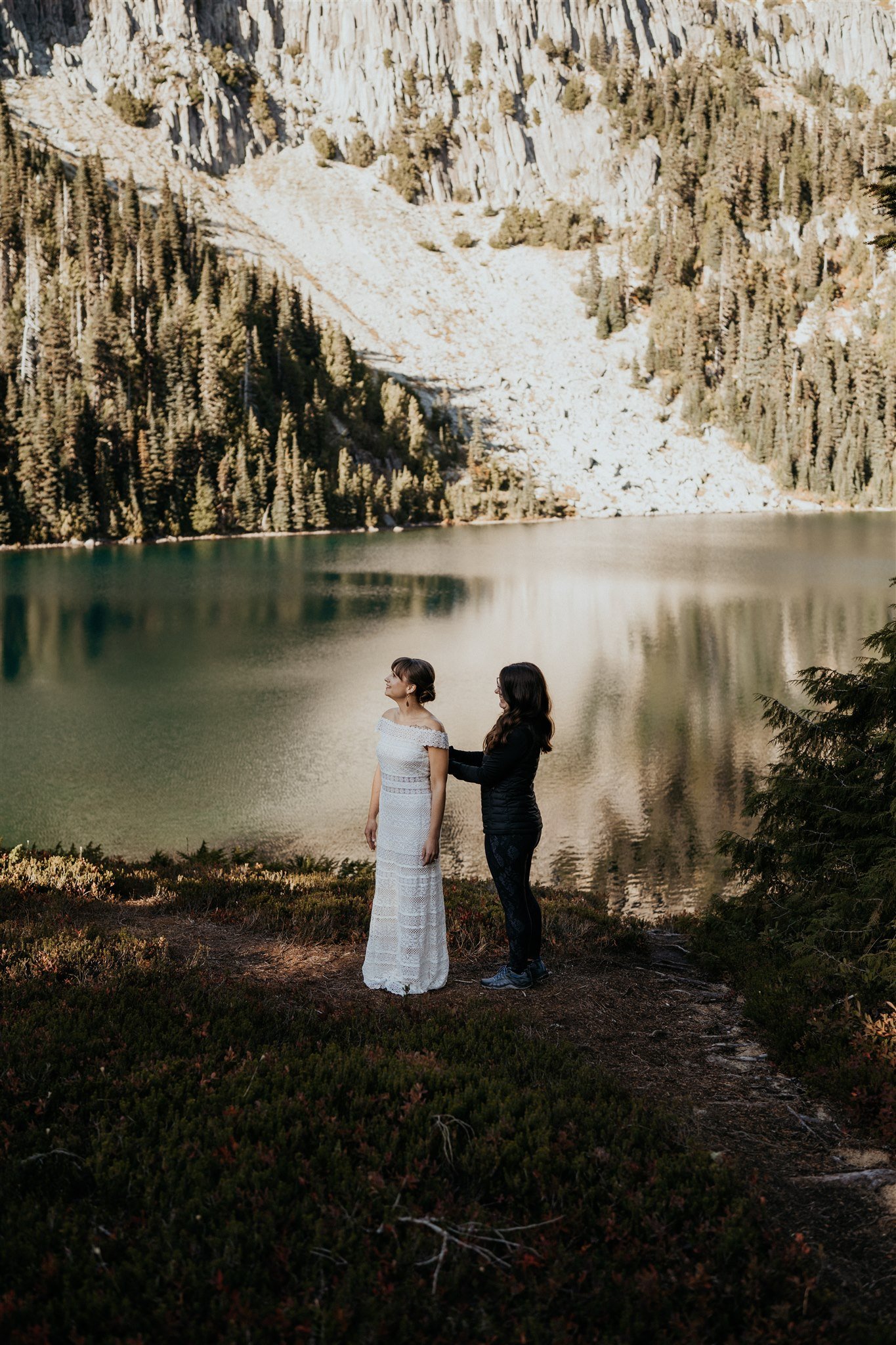 Woman helping bride into wedding dress for fall wedding at Mt Rainier