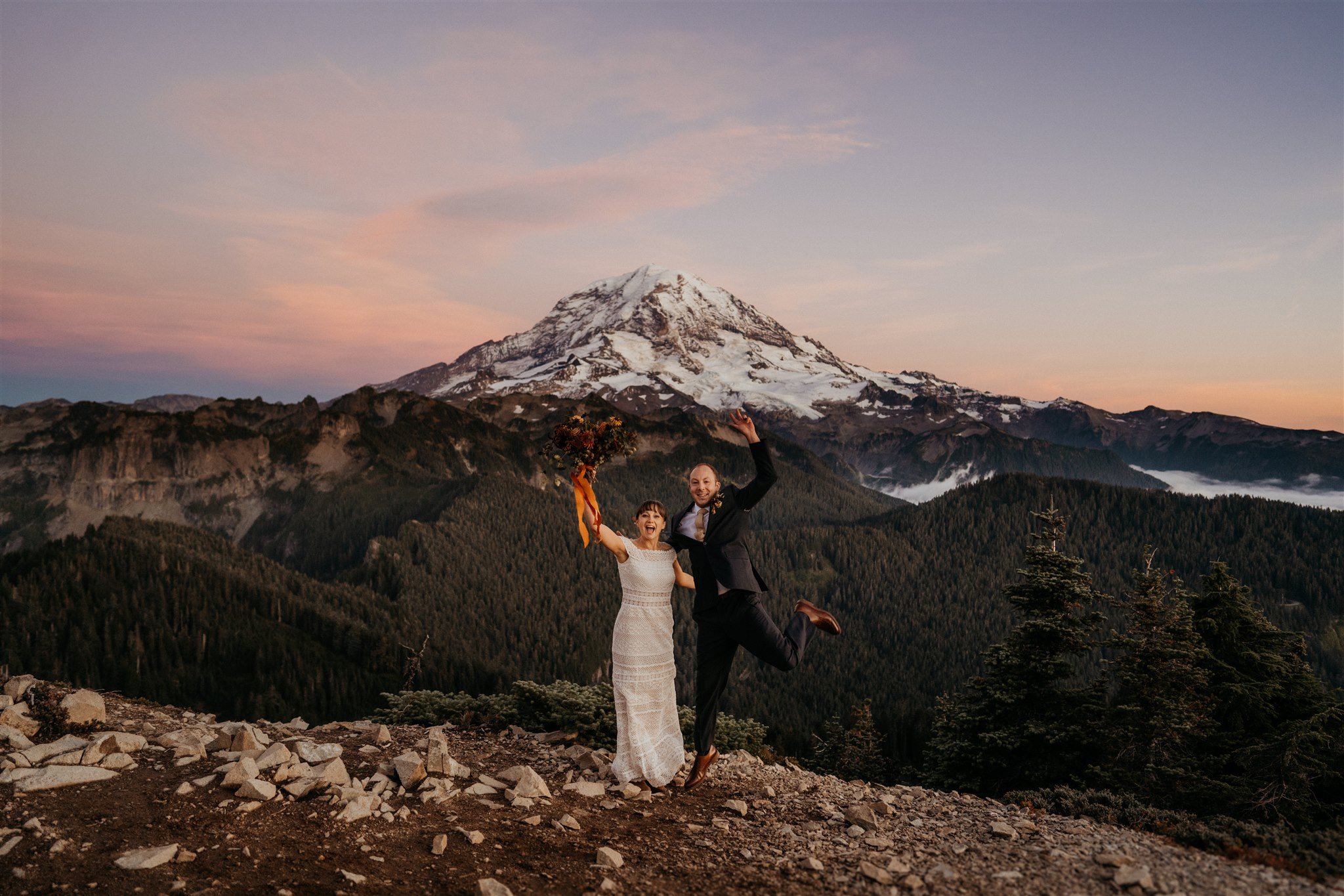 Bride and groom cheer and jump after autumn wedding ceremony at Mount Rainier National Park