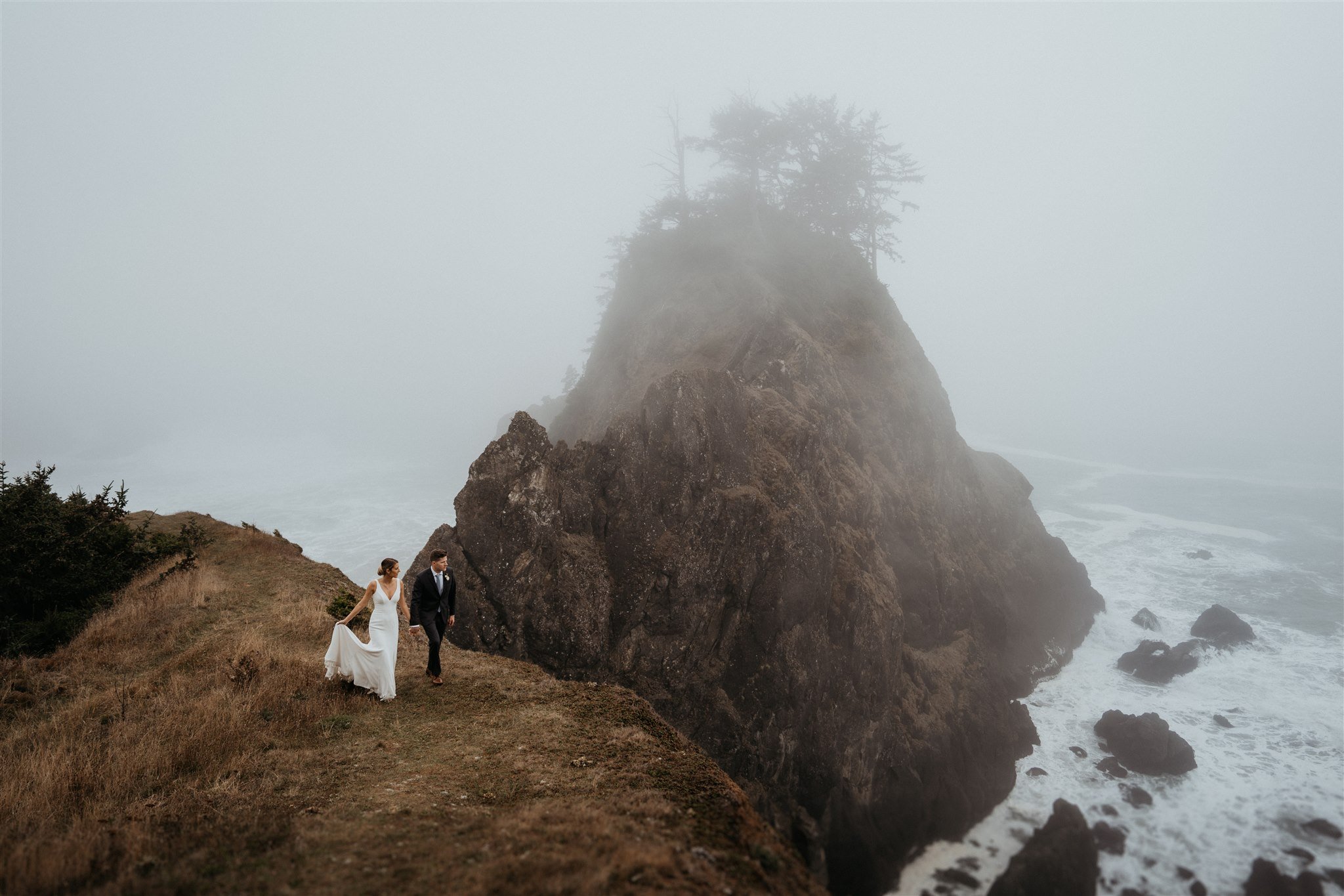 Bride and groom holding hands walking along the cliffs on the Southern Oregon Coast