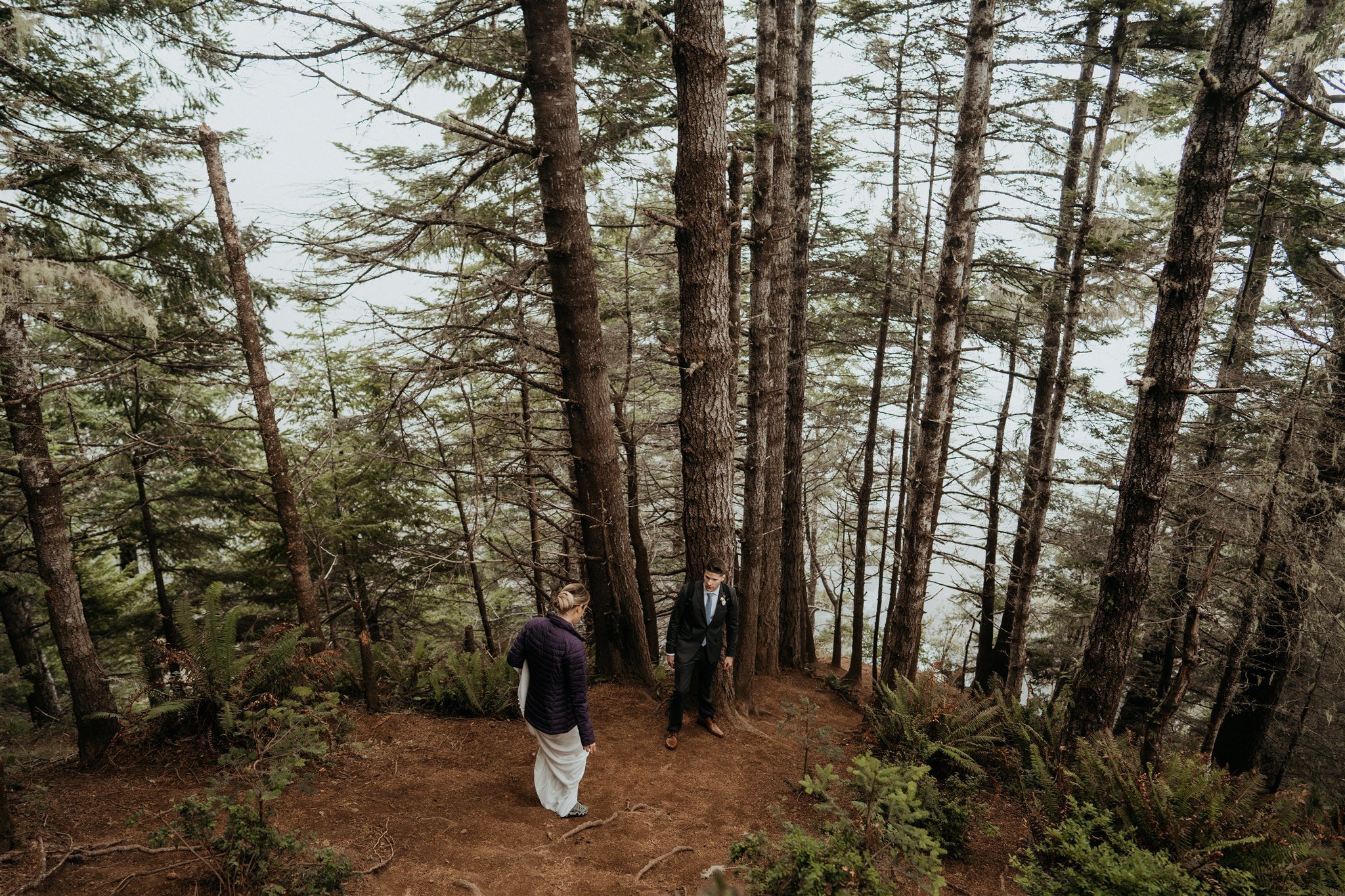 Bride and groom descending down a trail in the forest on the Southern Oregon Coast