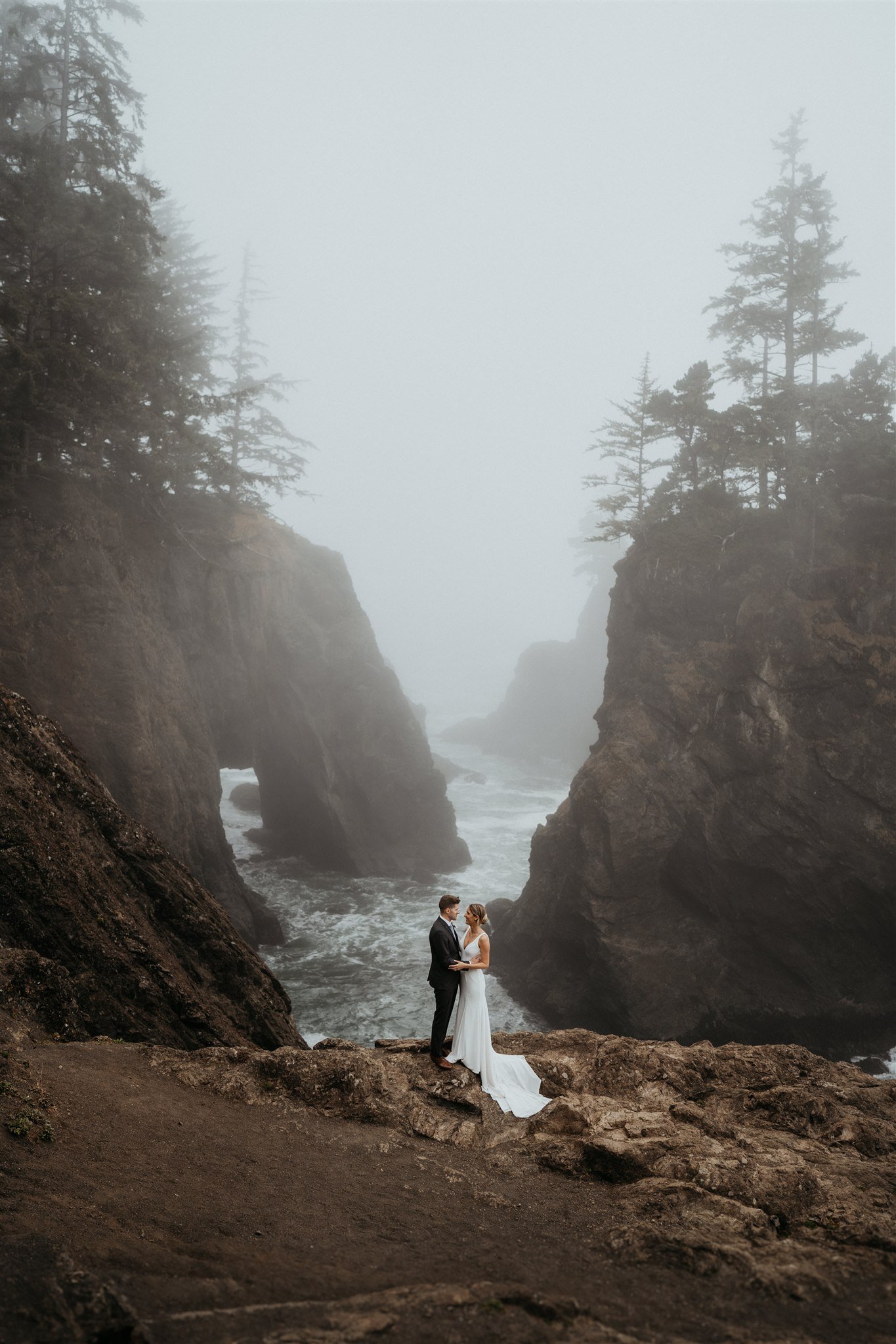 Bride and groom standing on the edge of a cliff on the Southern Oregon Coast