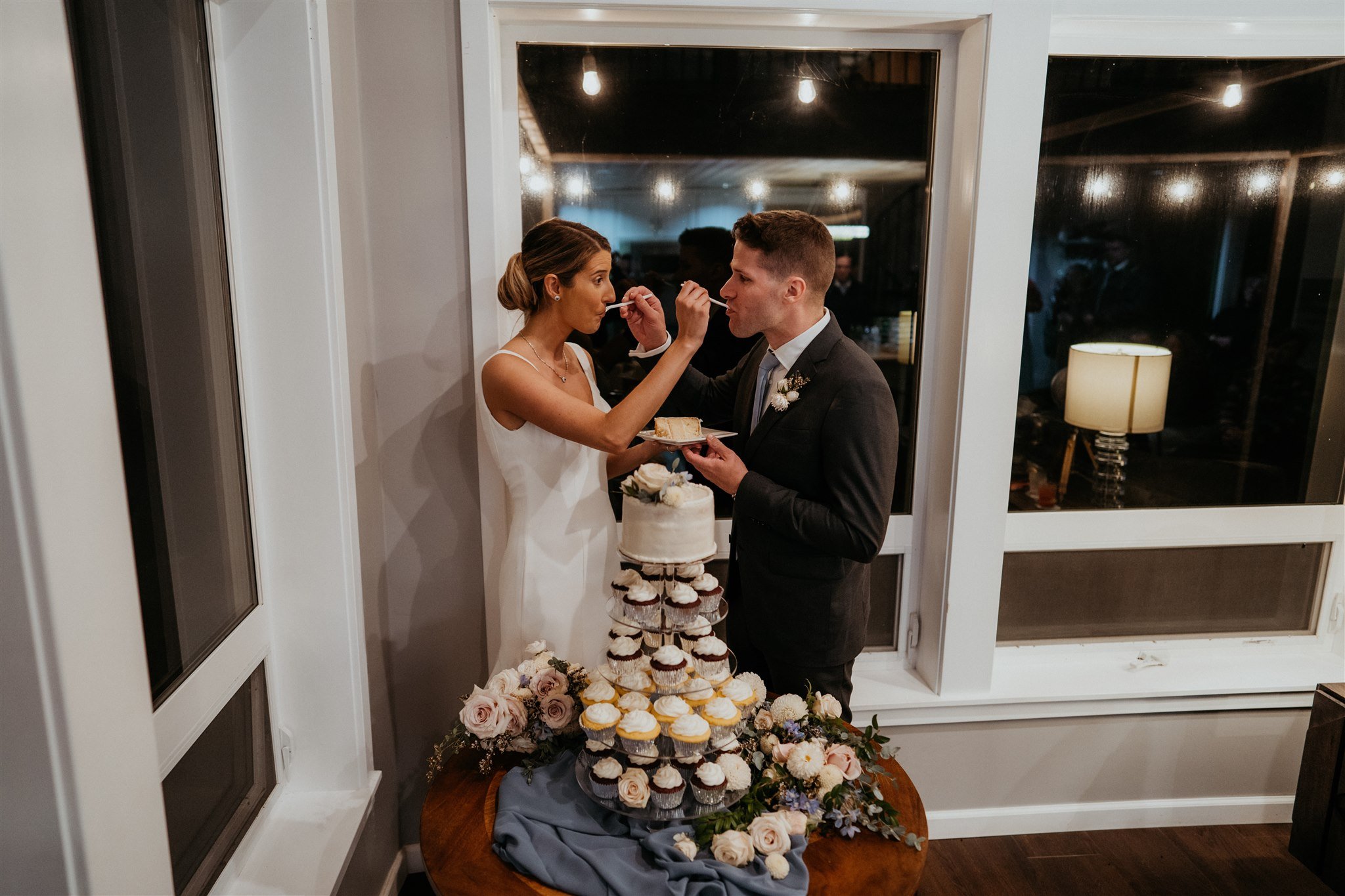 Bride and groom feeding each other cake at intimate wedding reception