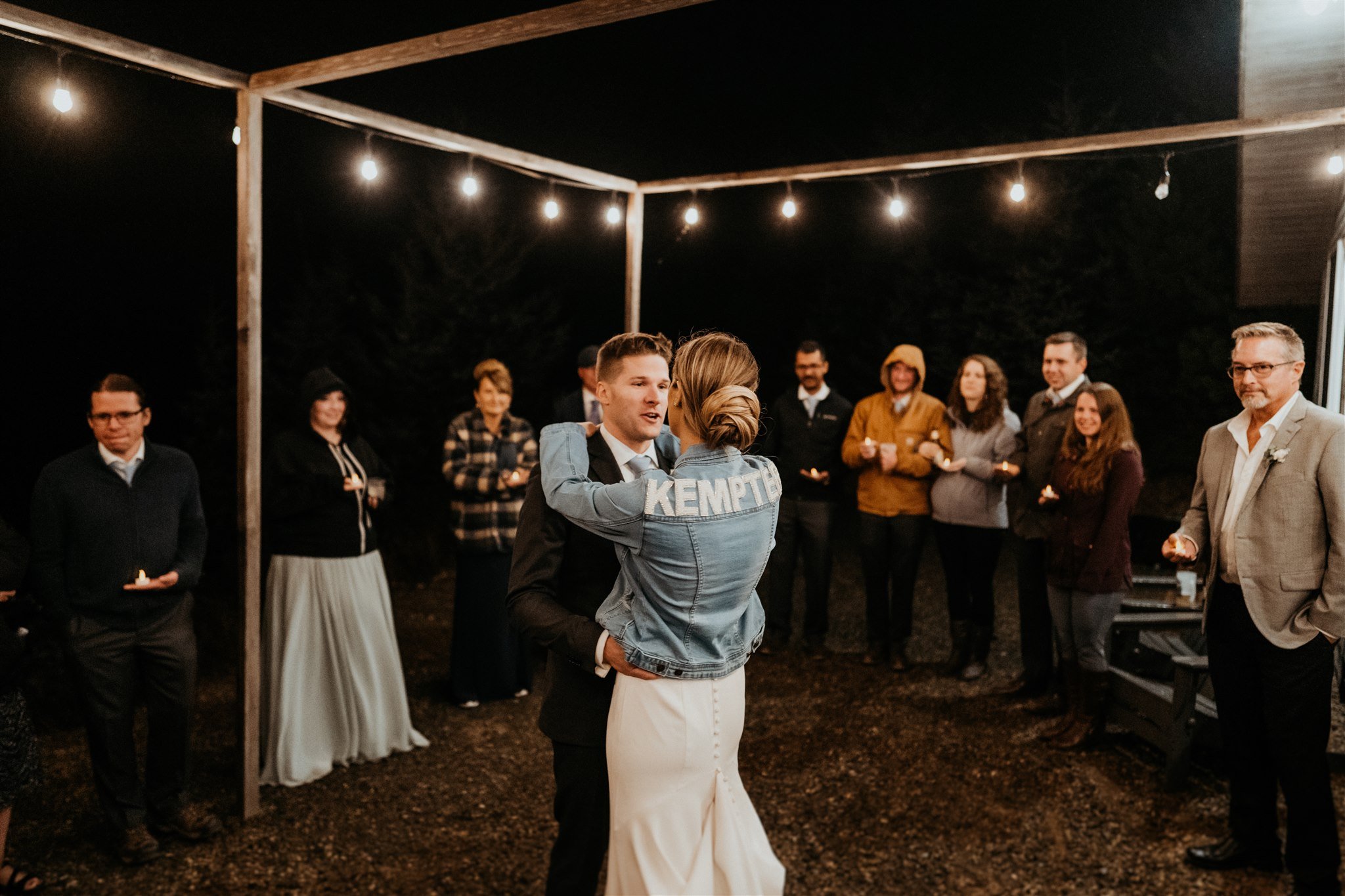 Bride and groom dancing under string lights at outdoor intimate wedding reception