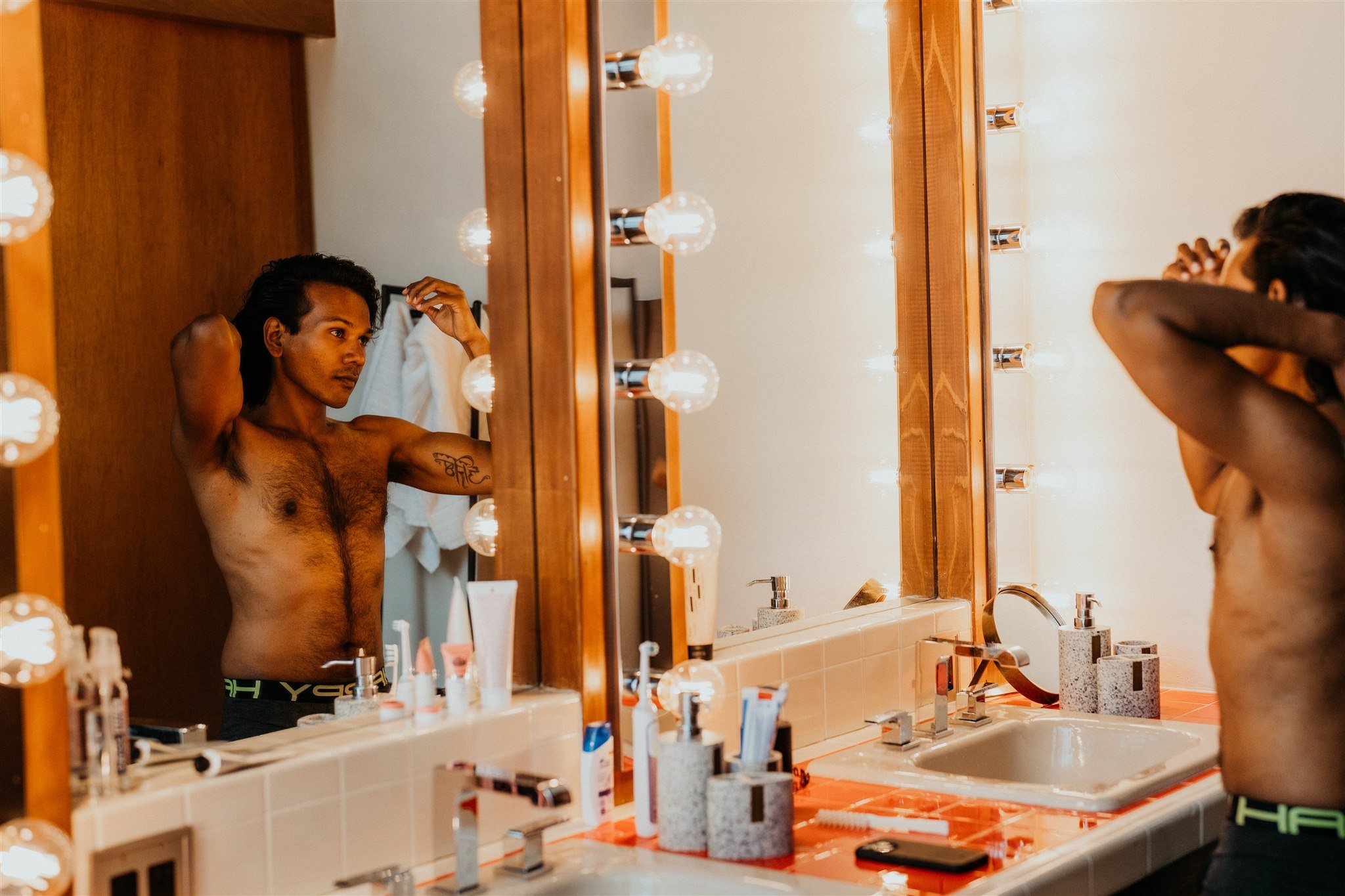 Groom combing hair in front of lightbulb mirror