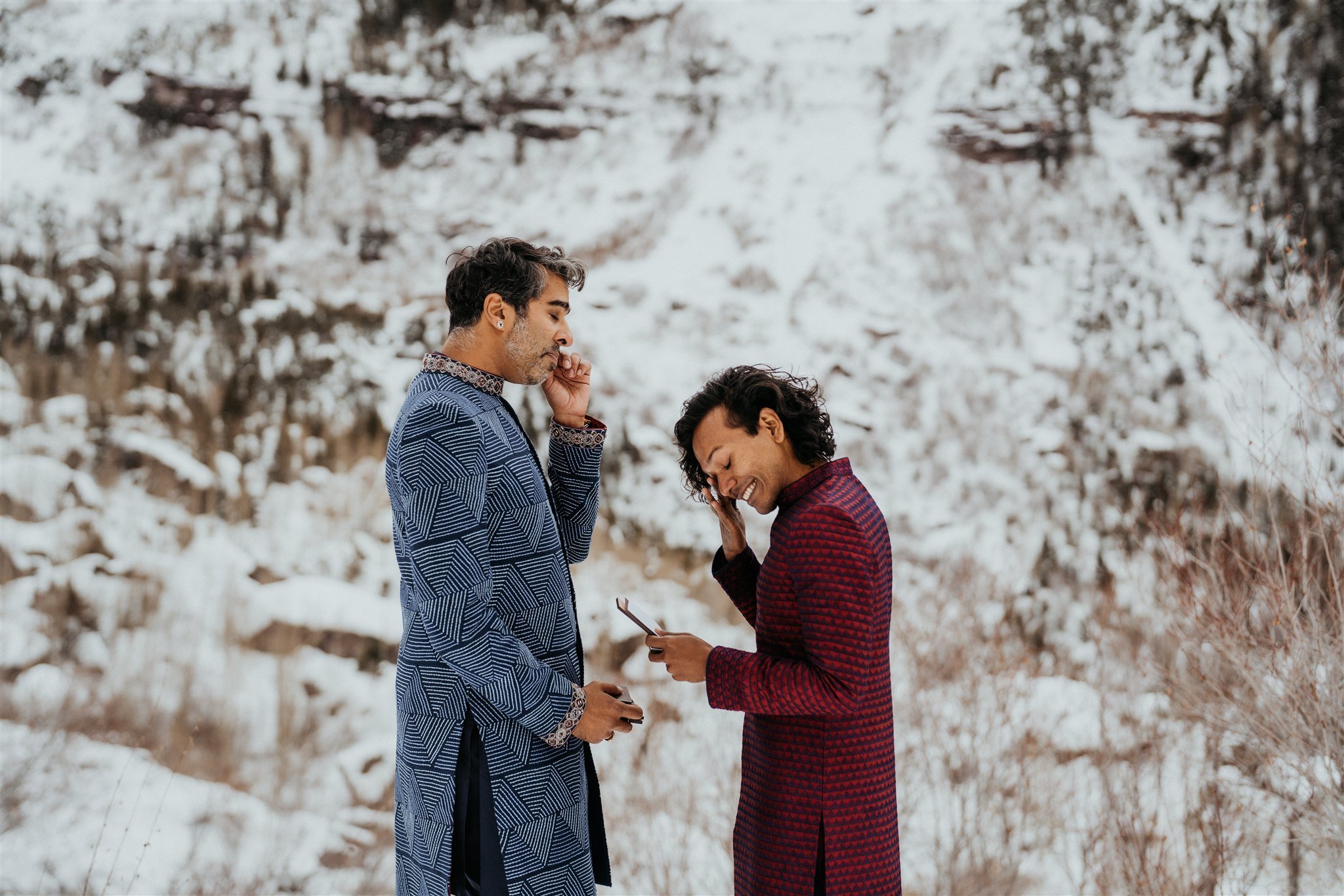 Two grooms wiping away tears during winter elopement in the Colorado mountains