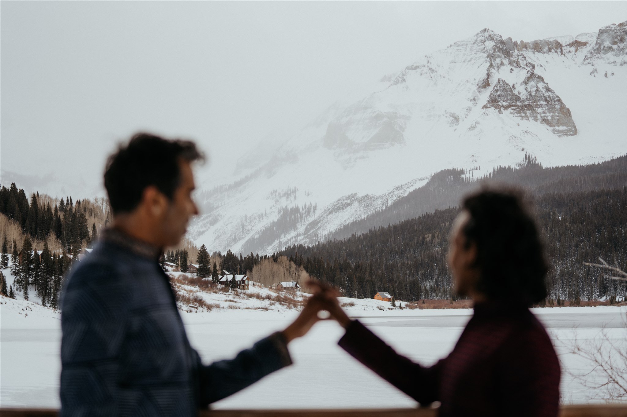 Grooms interlocking hands in front of the Colorado mountains 