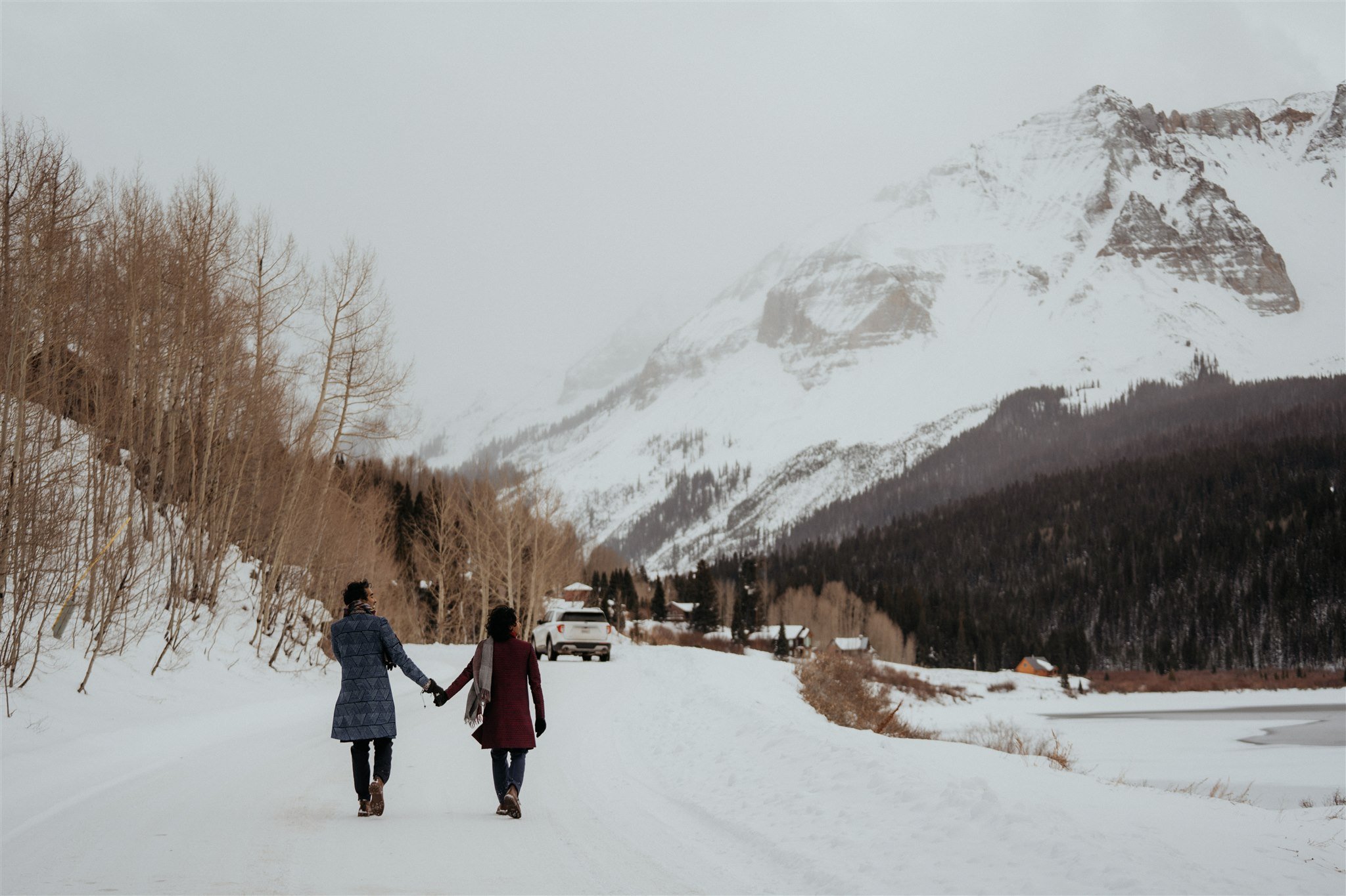 Two grooms walking hand in hand to their car after their winter elopement in the Colorado mountains