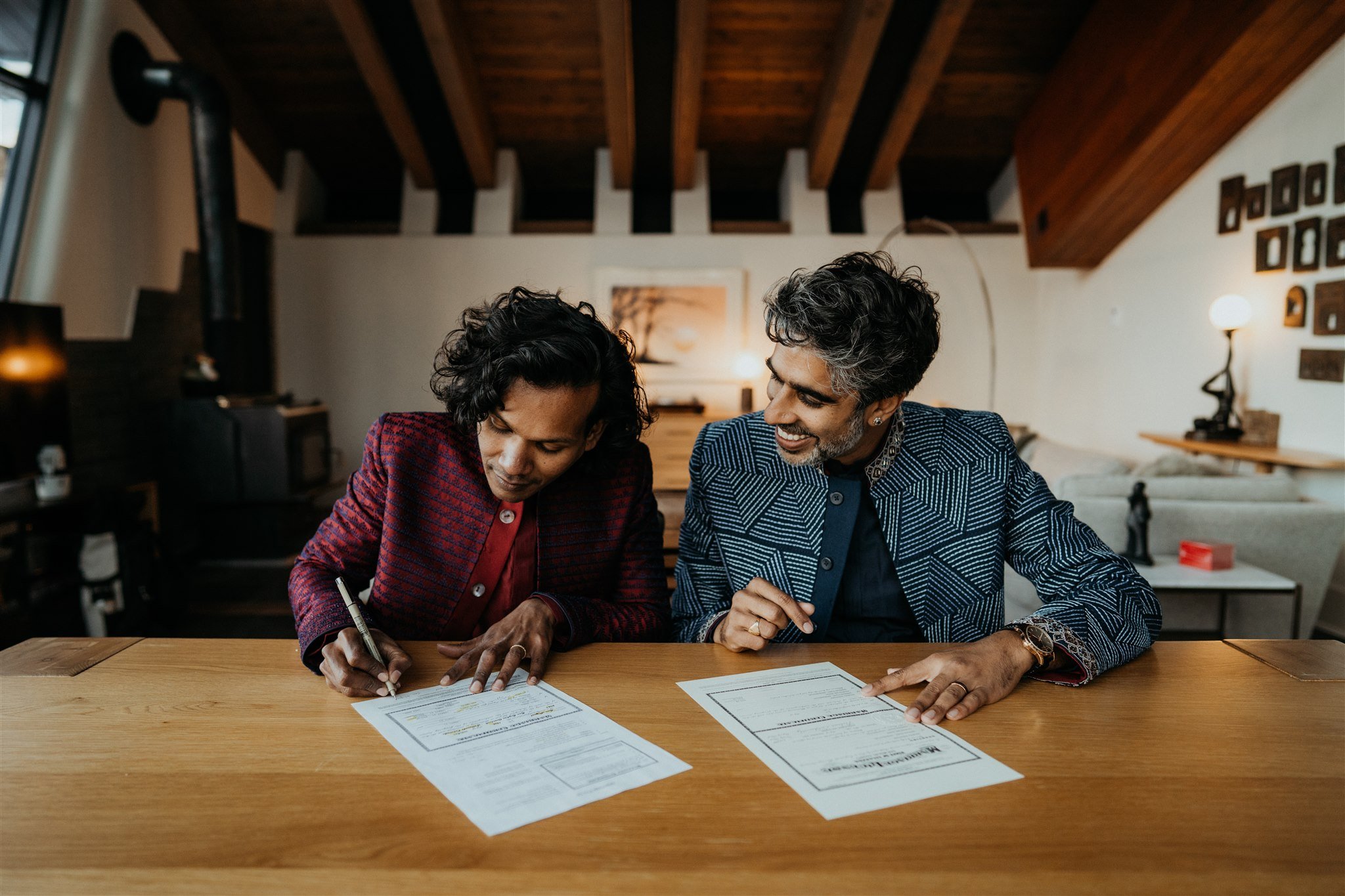 Two grooms signing marriage license in their Colorado mountain cabin