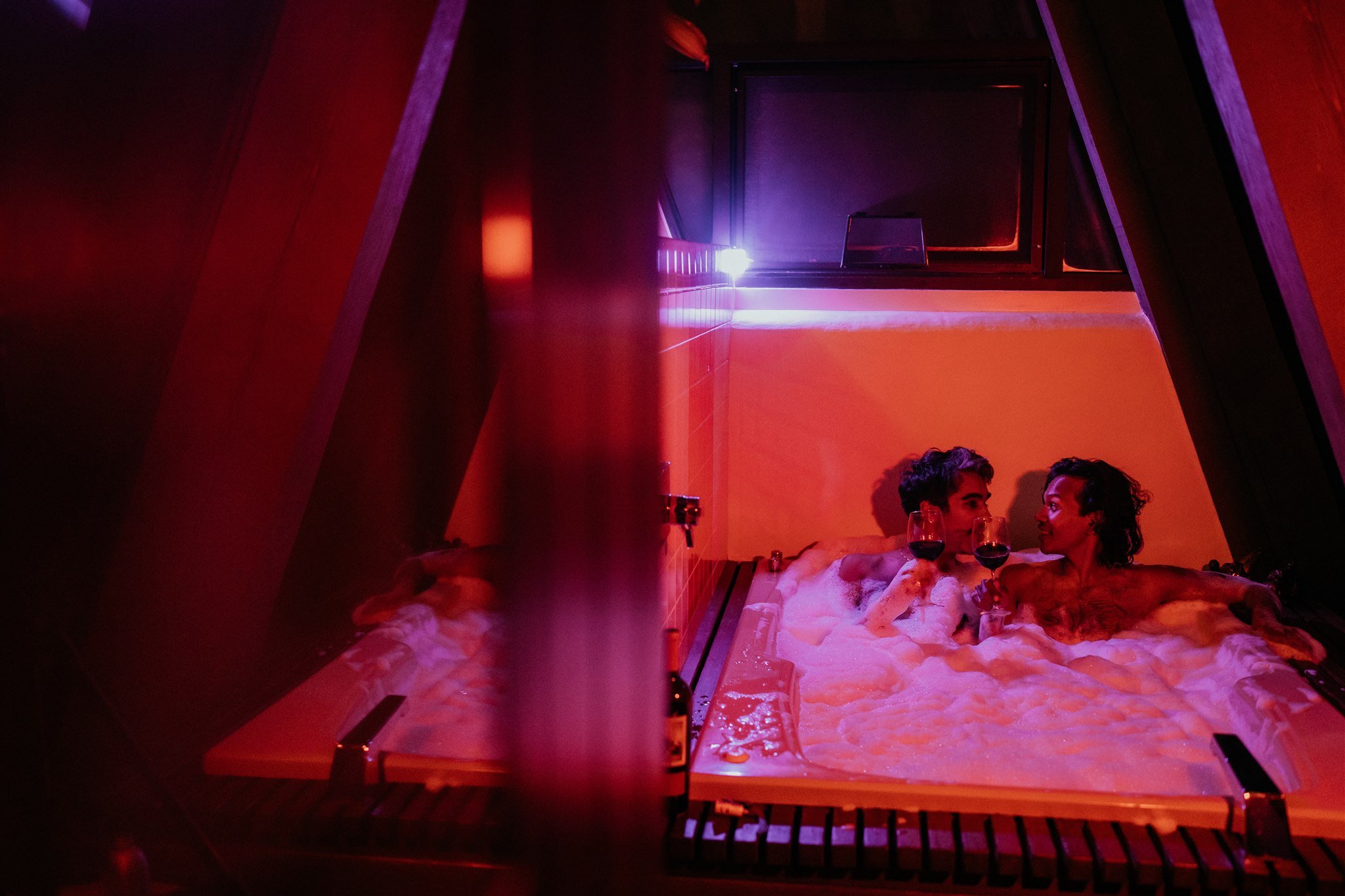 Two grooms toasting with wine in a hot tub 