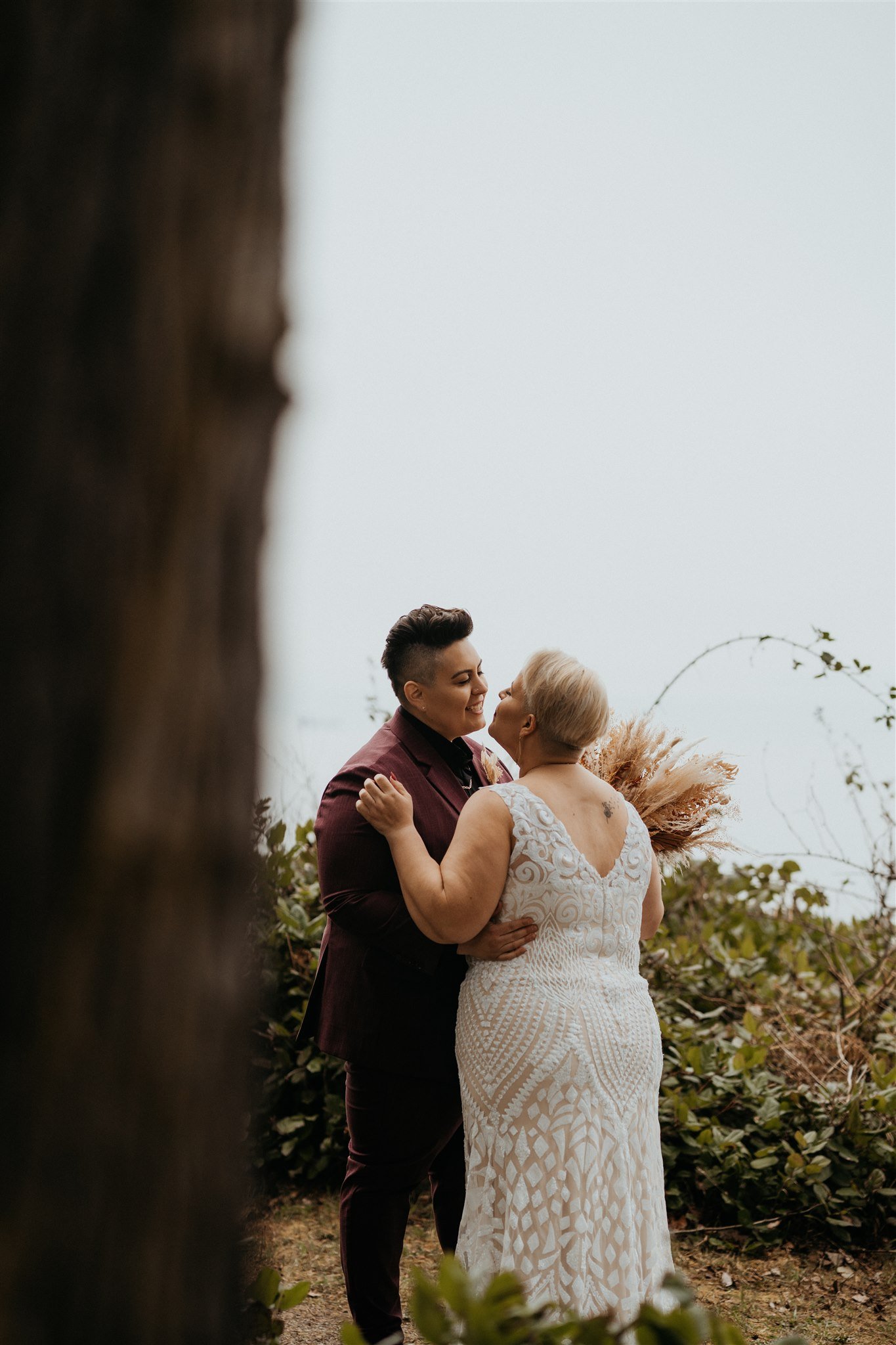 Two brides kissing in the forest before their PNW elopement ceremony