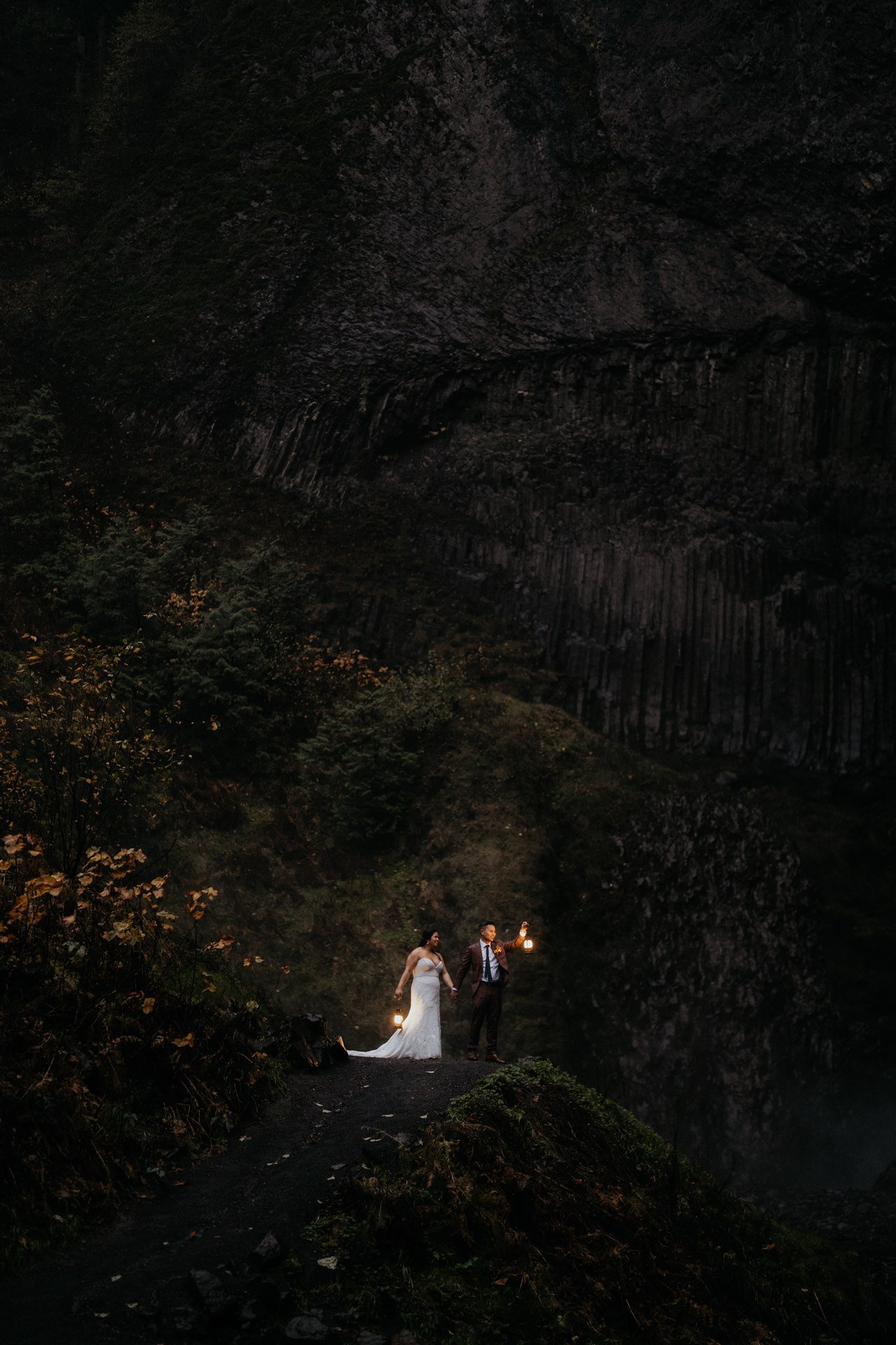 Bride and groom holding lanterns at Oregon waterfall wedding