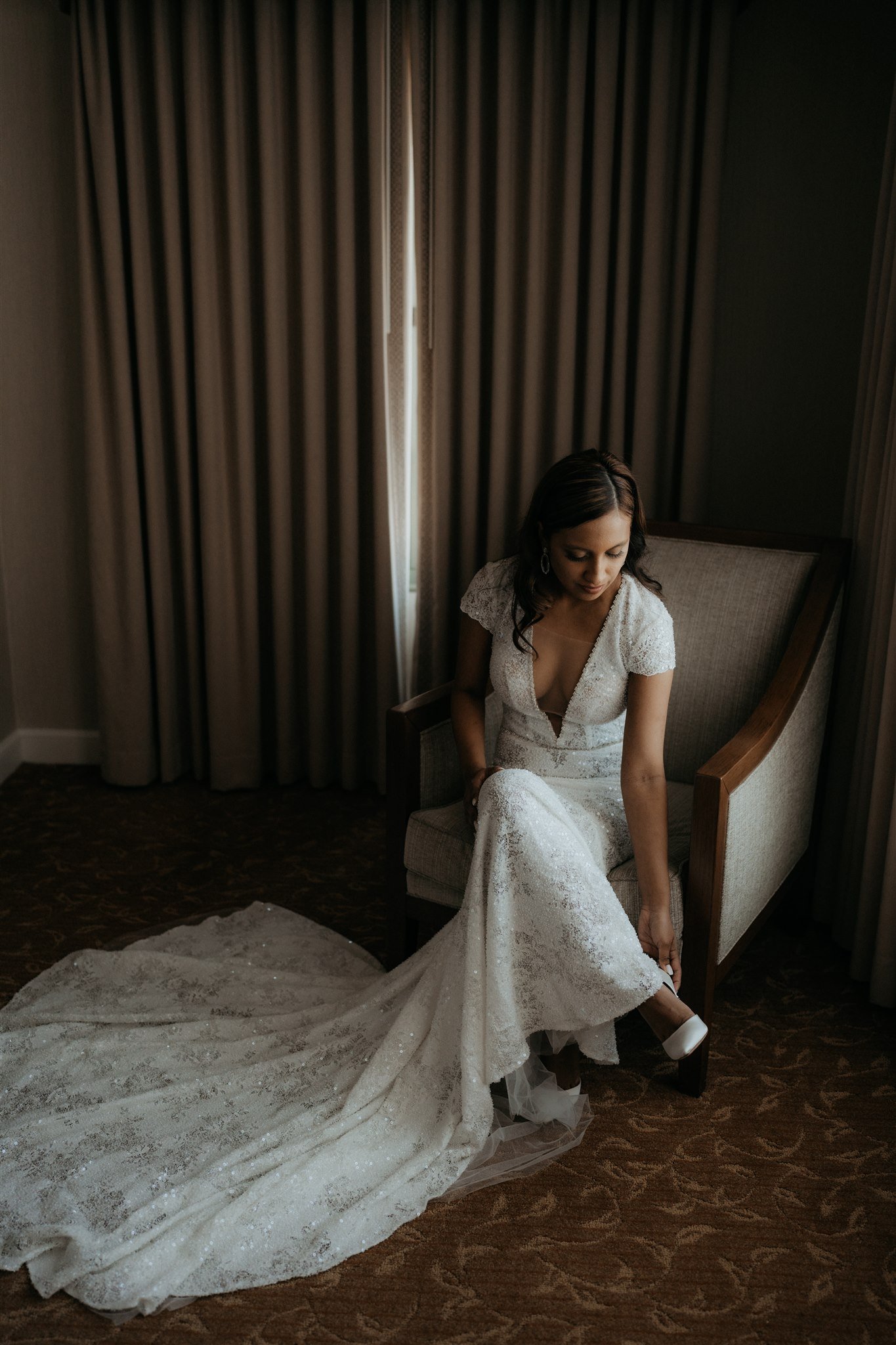 Bride in white sequin dress putting on white heels for Big Sur Elopement