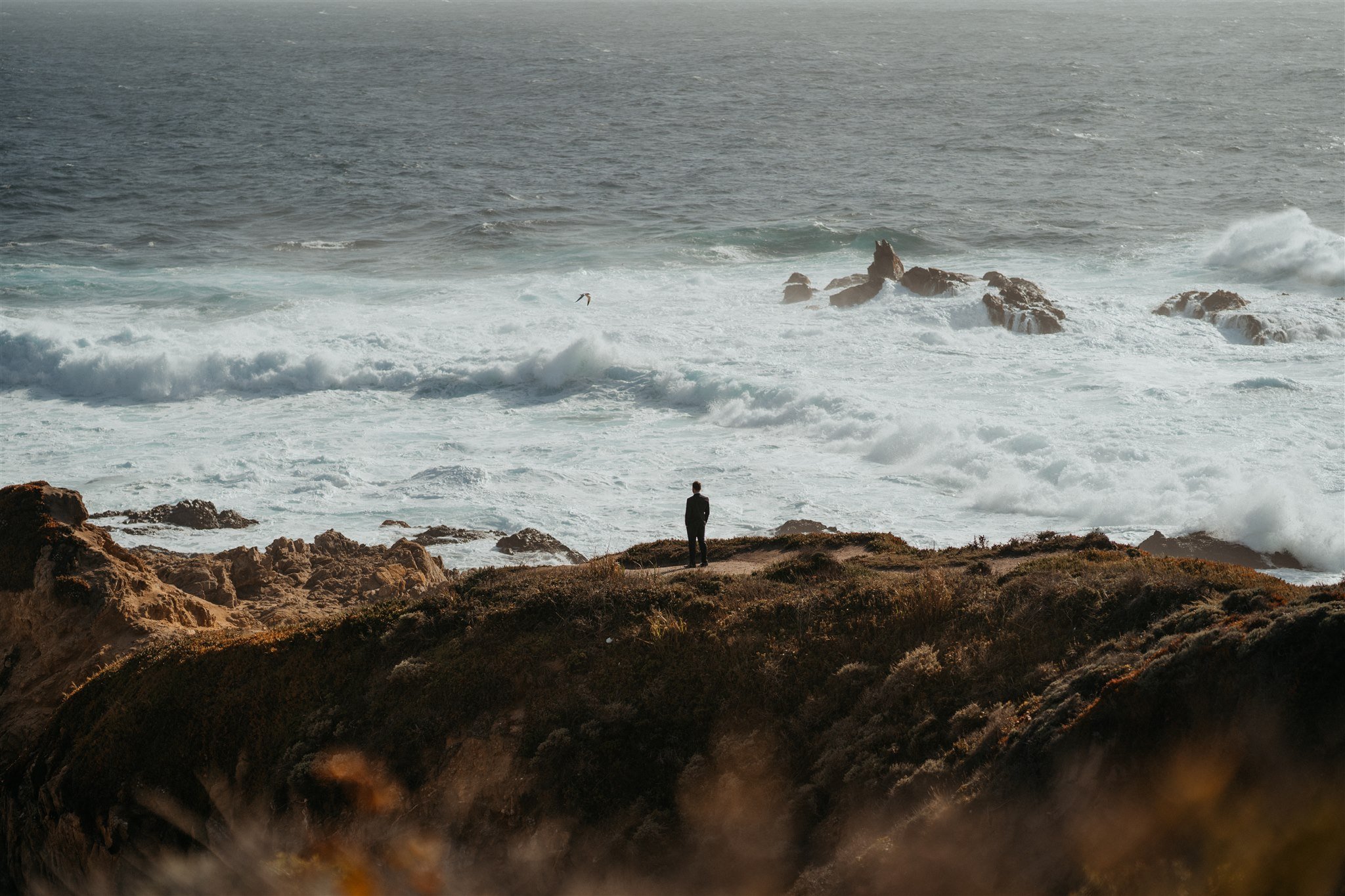 Groom standing on a cliff at a Big Sur elopement location