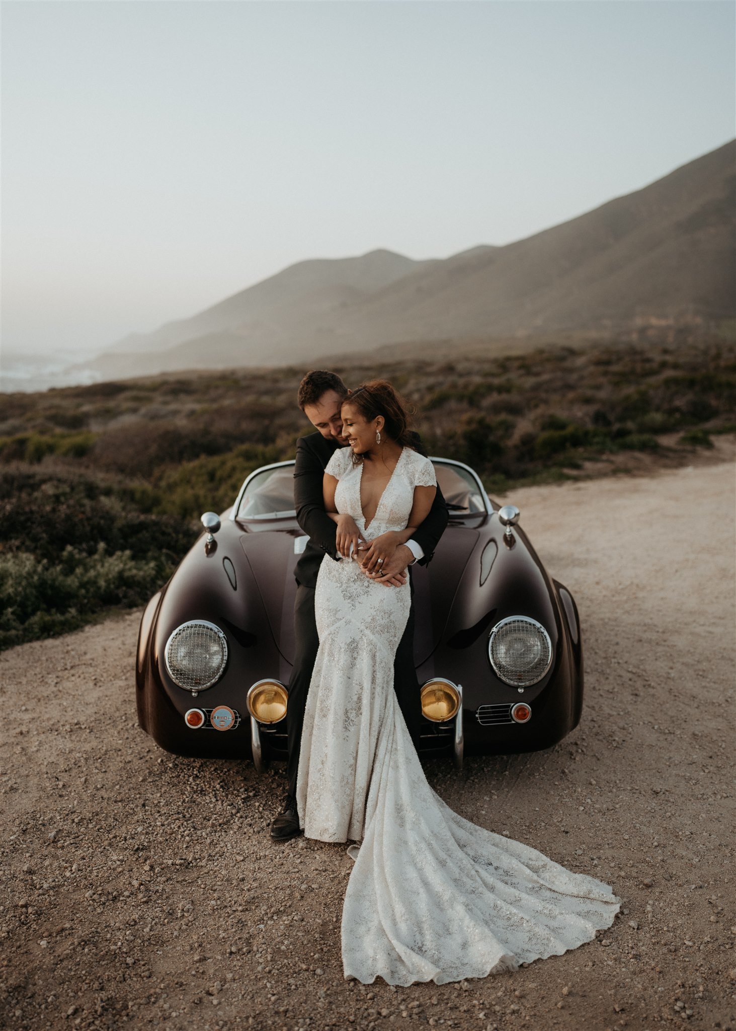 Bride and groom lean against vintage convertible car at Big Sur elopement location