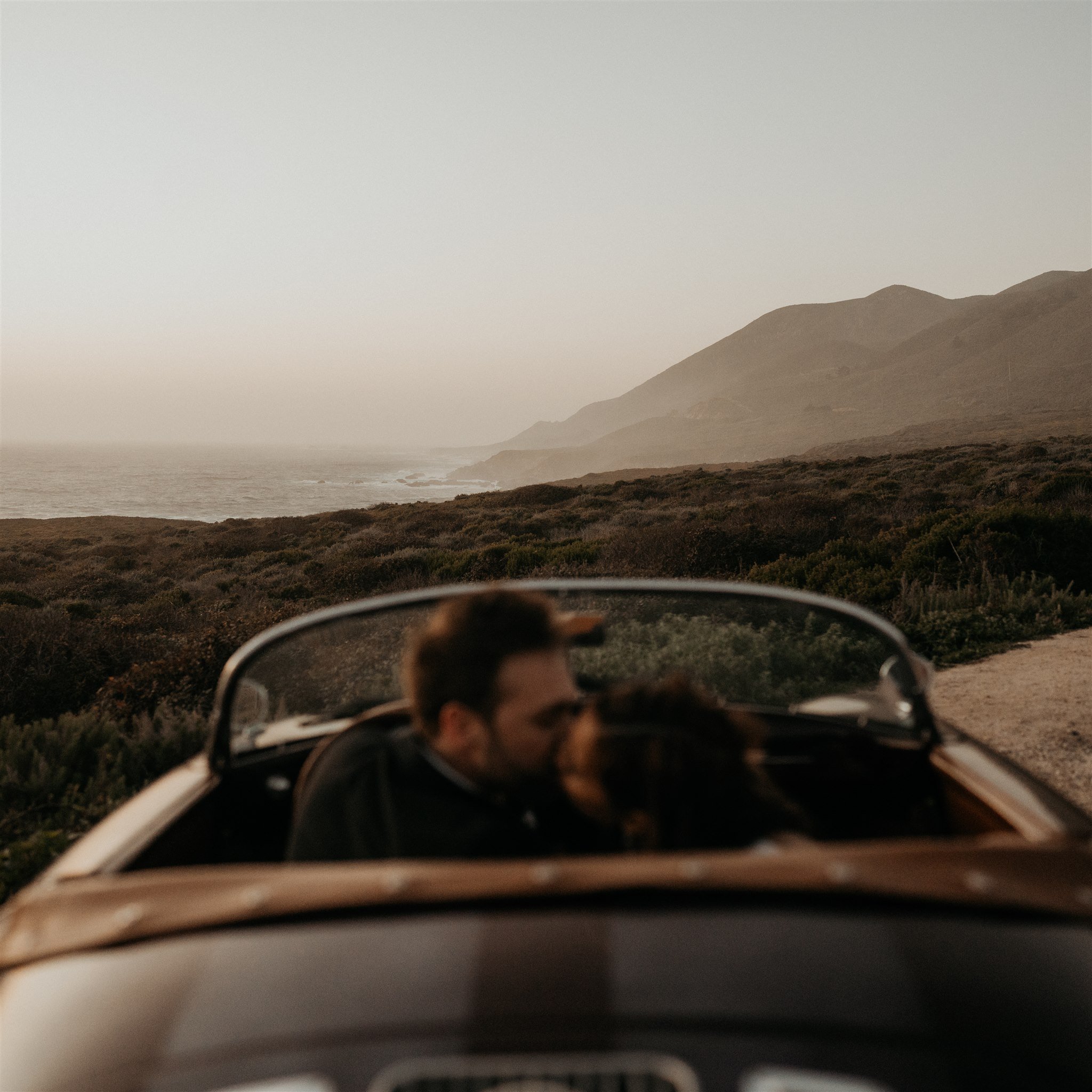 Bride and groom kiss in a vintage convertible car at their Big Sur elopement