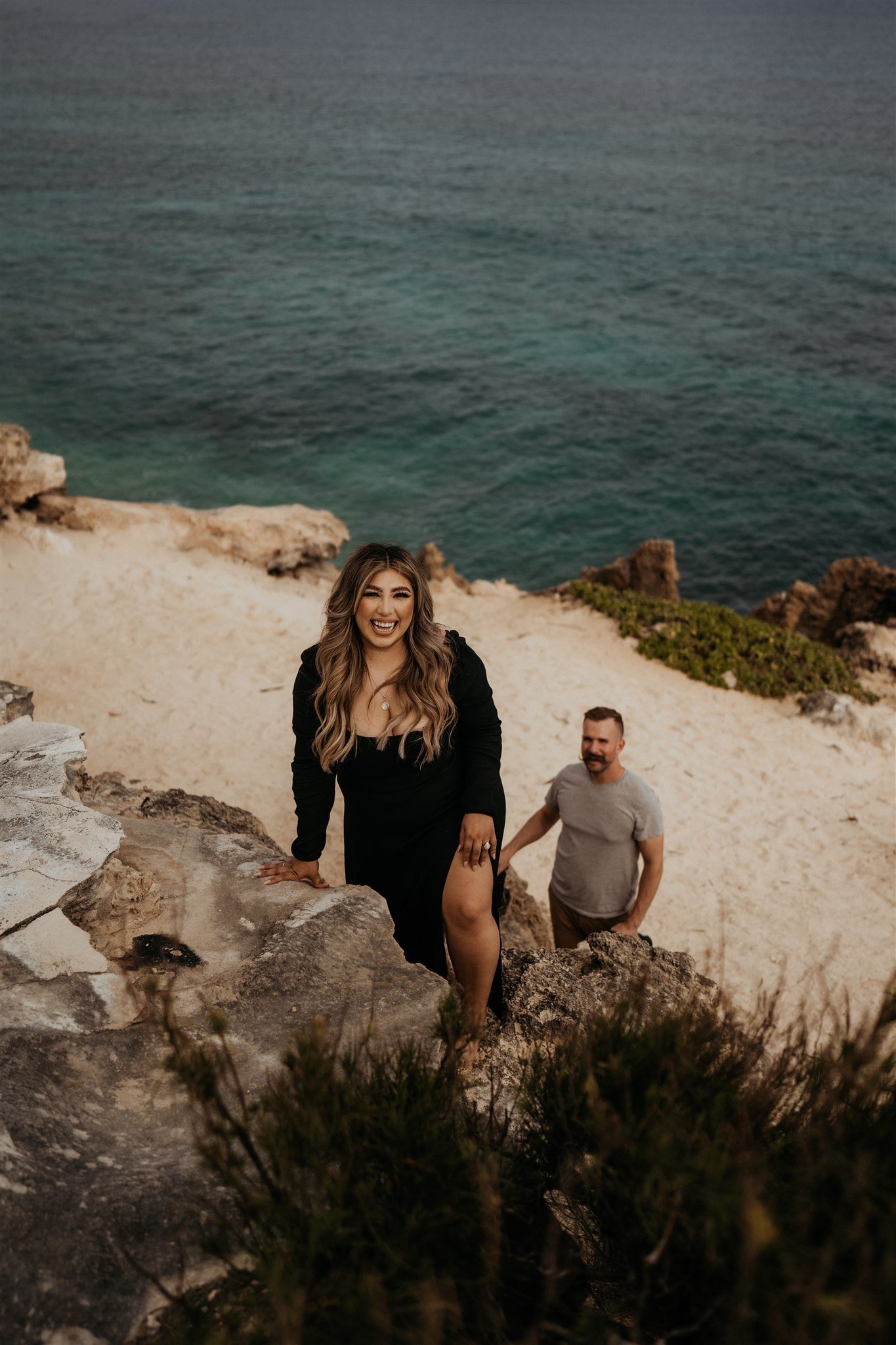 Couple climbing up a cliff during Hawaii engagement photos
