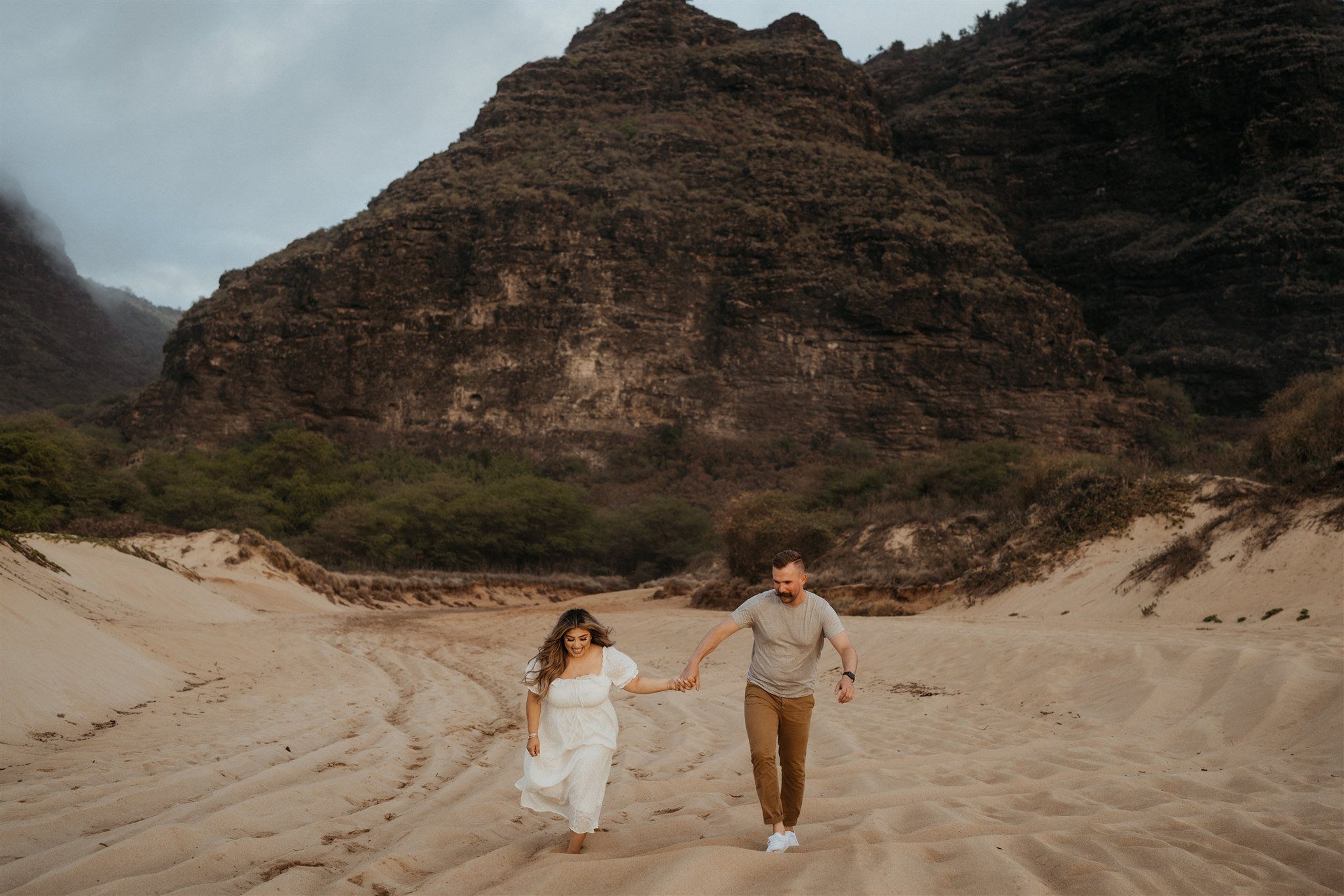 Couple running across the beach during Hawaii engagement photo session