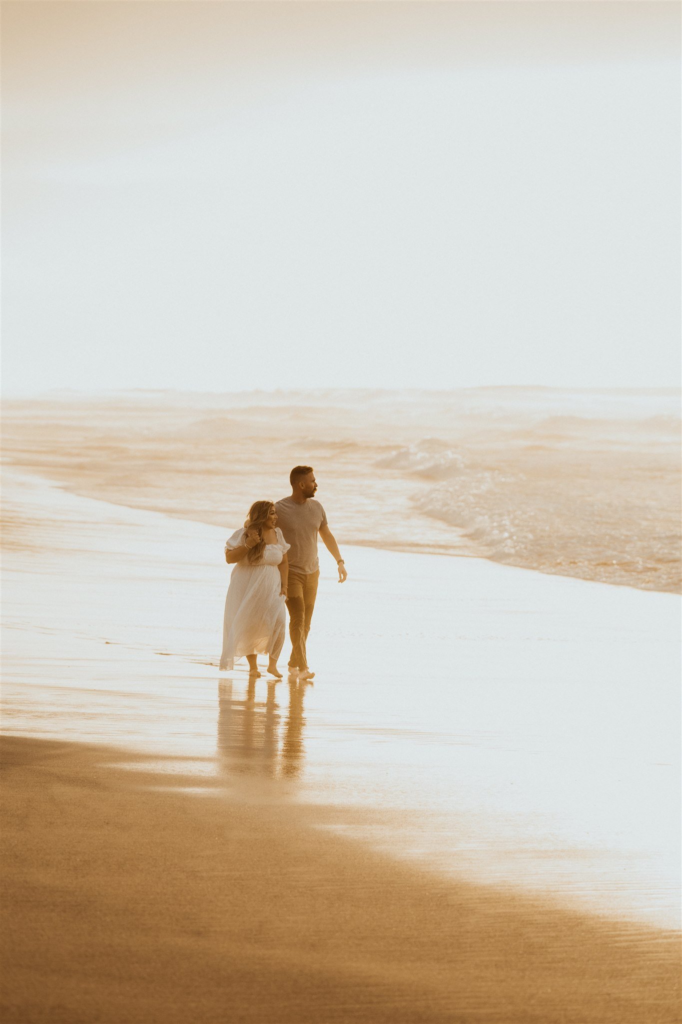Couple walking across the beach during Hawaii engagement photos