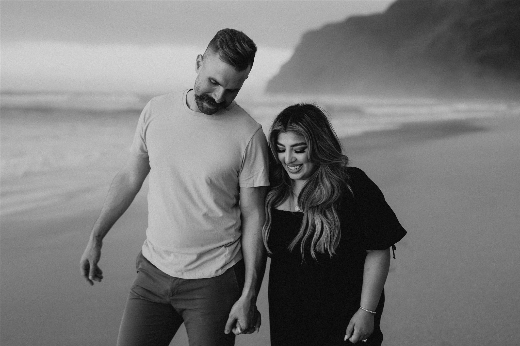 Couple holding hands, walking along the beach in Kauai for Hawaii engagement photos