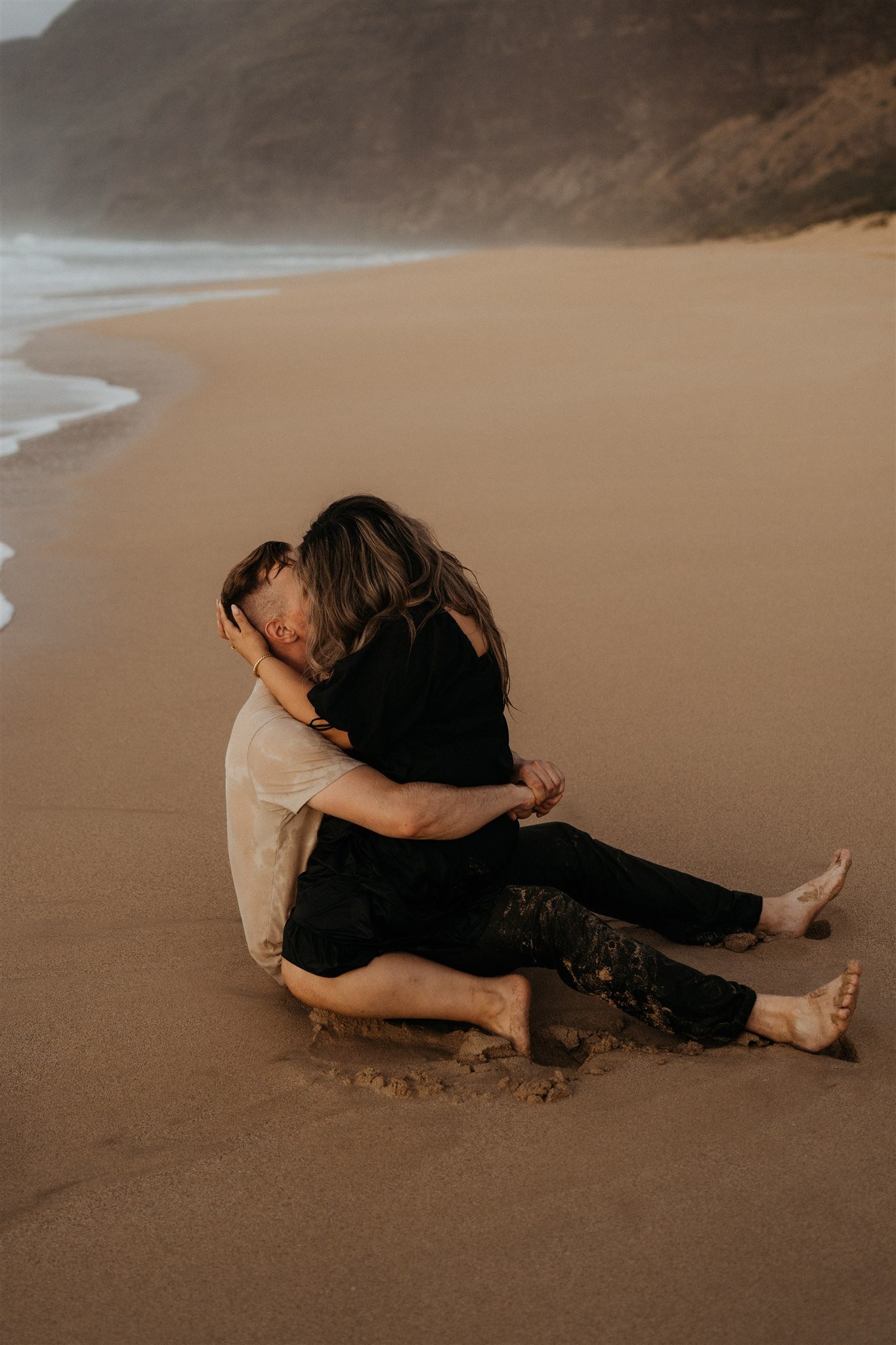 Couple sitting on the beach in Kauai during engagement photoshoot