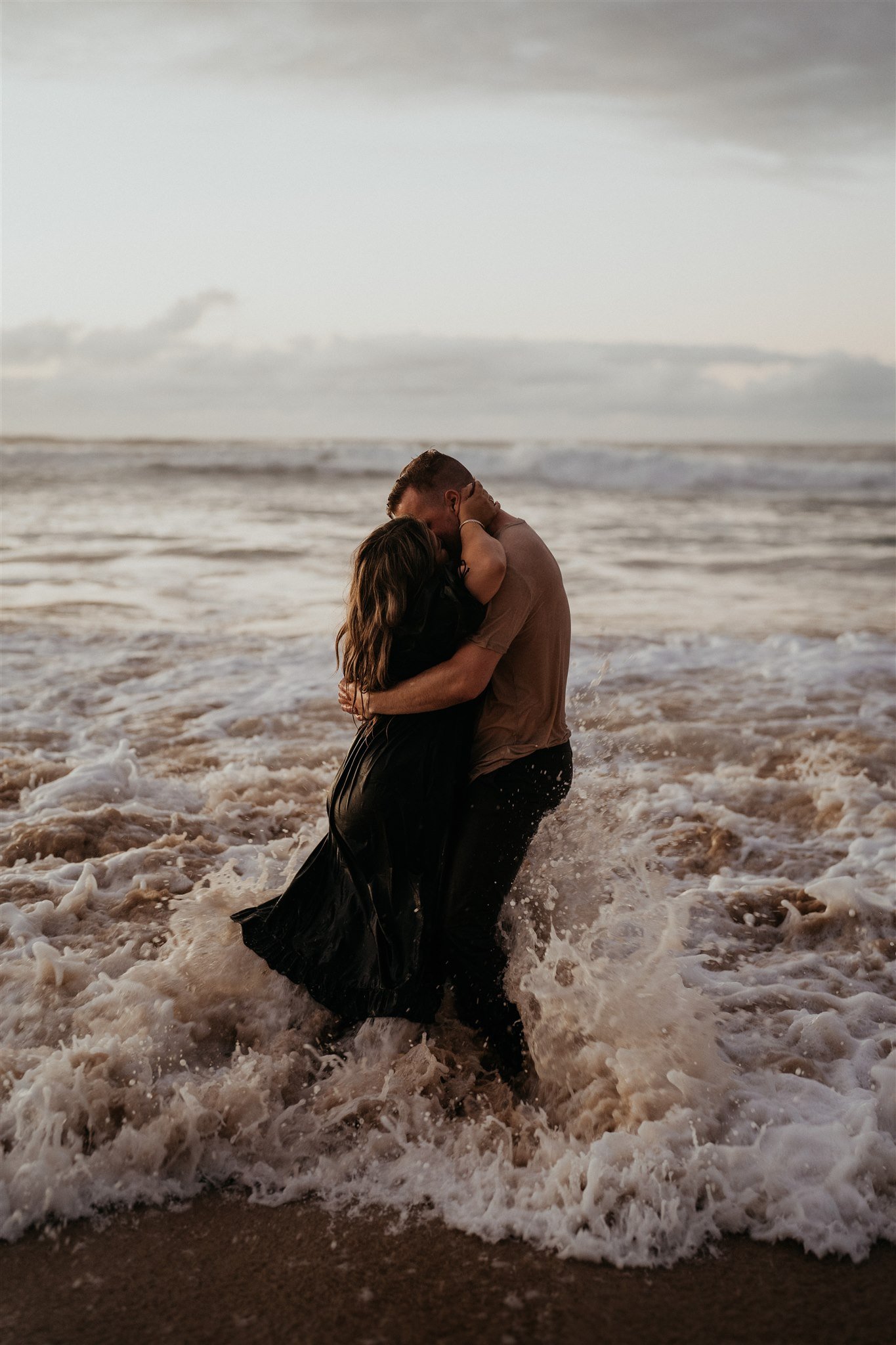 Couple standing in the ocean, kissing during Hawaii engagement photos
