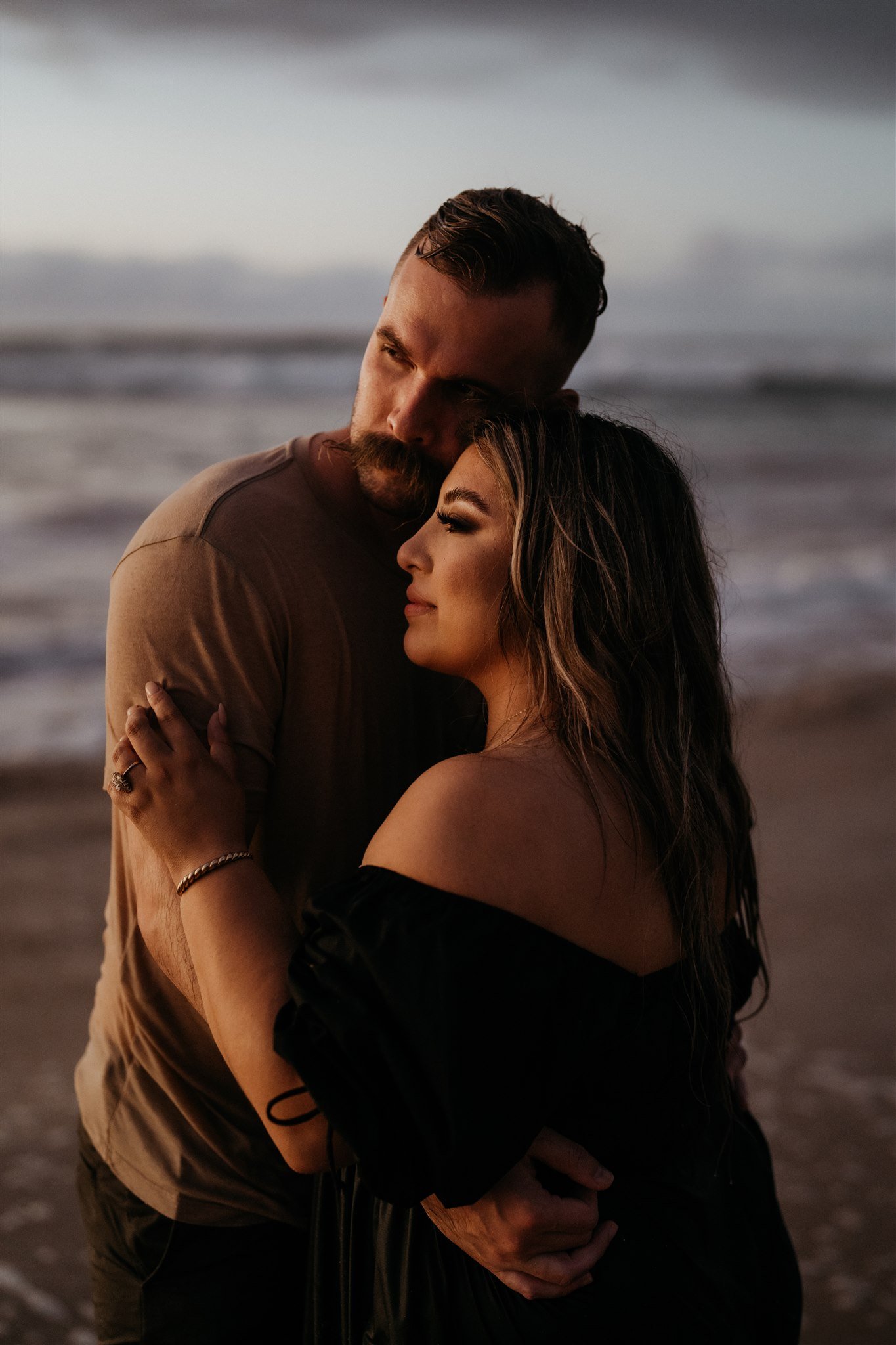 Couple hugging and watching the sunset during Hawaii engagement photo session
