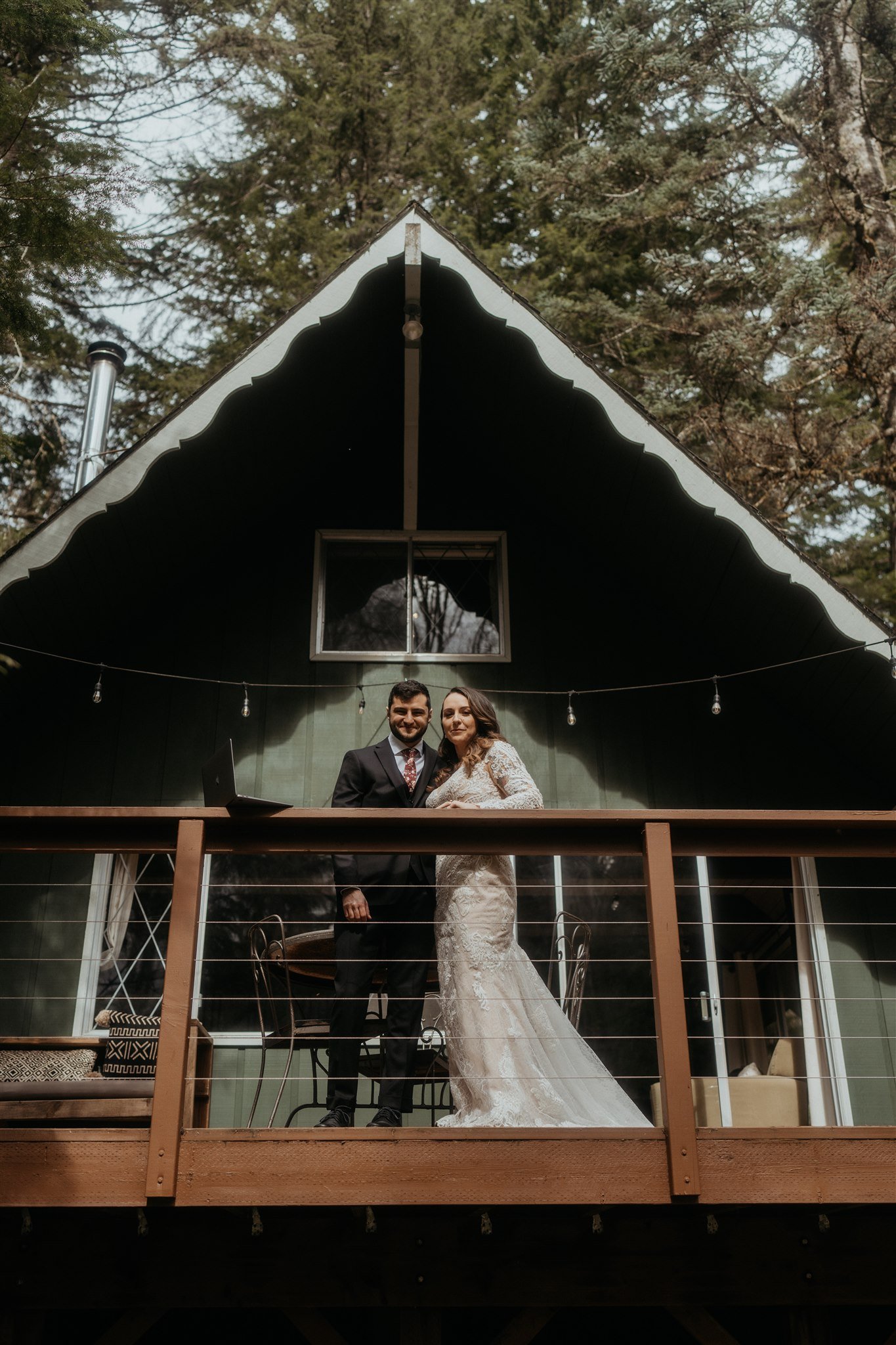 Bride and groom standing on the deck of their snowy mountain cabin