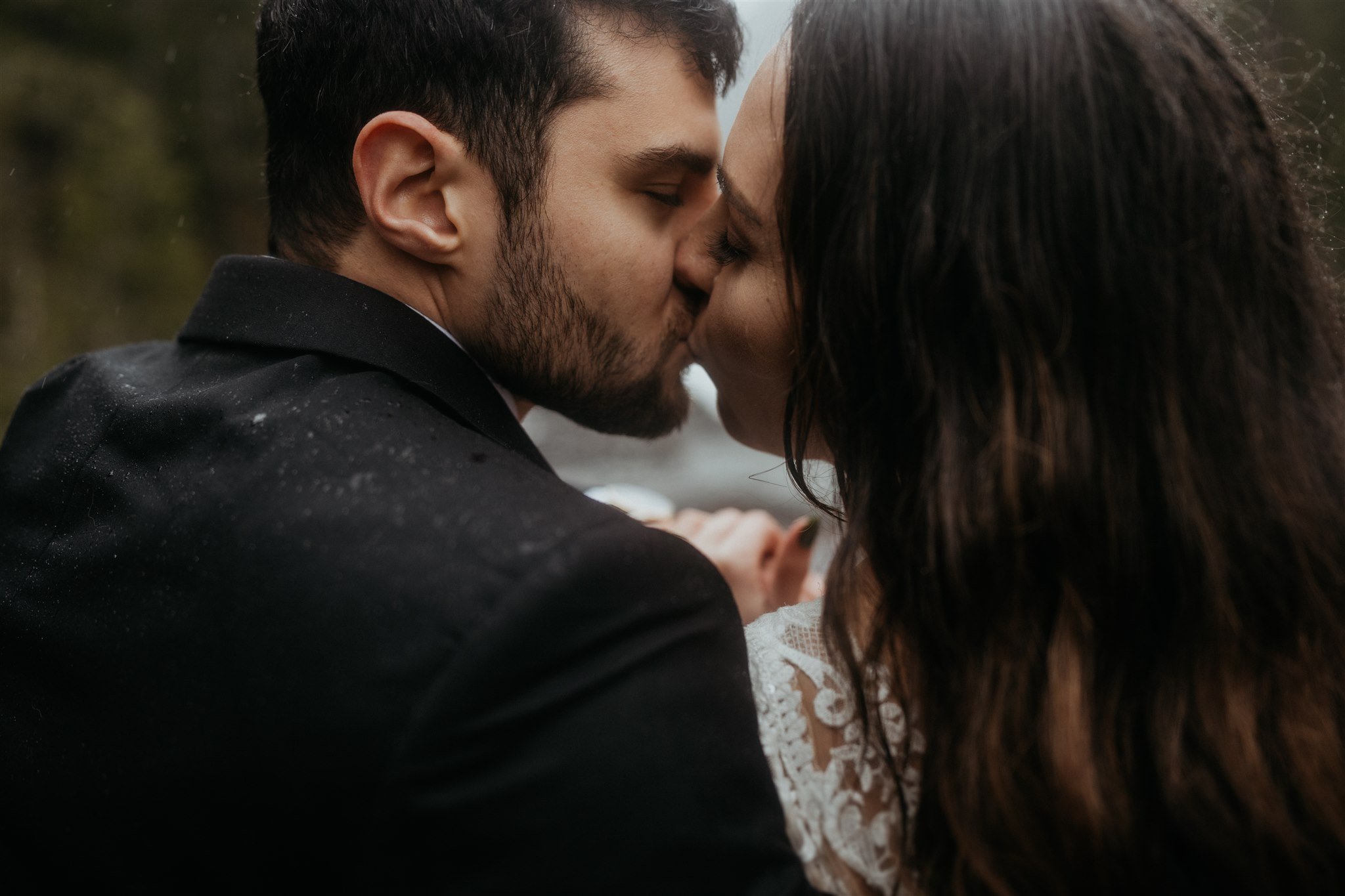 Bride and groom kissing on a bridge near Mt Rainier for their snowy mountain elopement