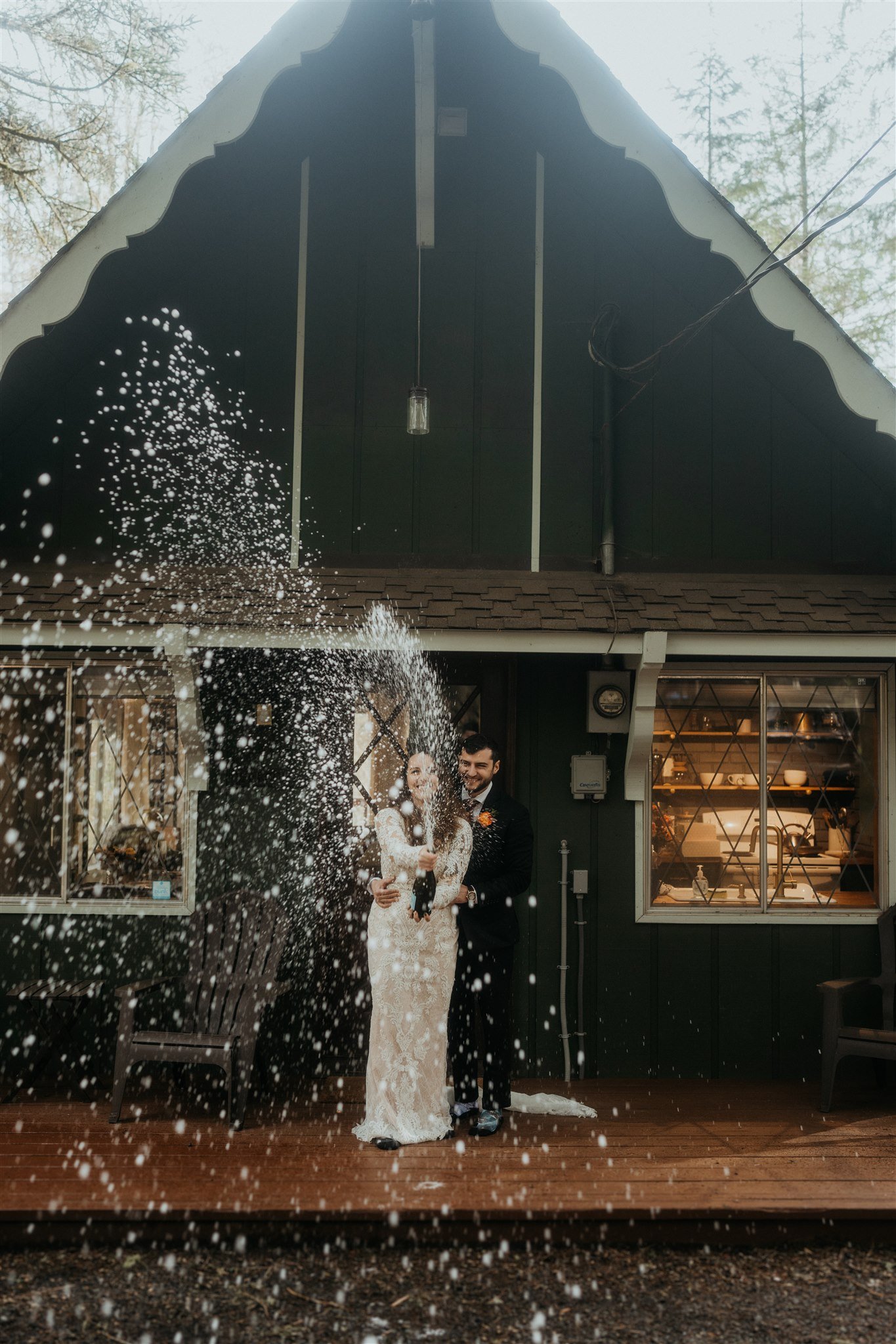 Bride and groom spray champagne in front of mountain cabin in Mt Rainier