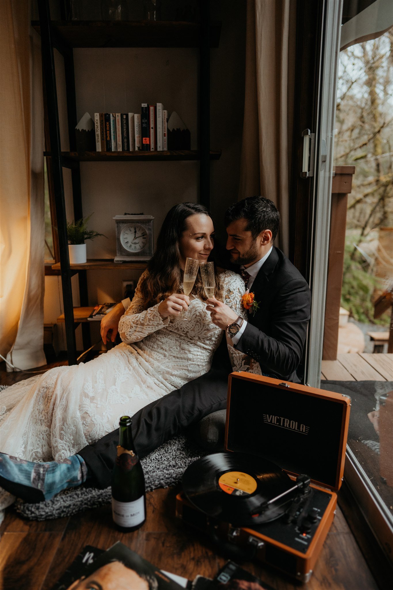 Bride and groom sit on the floor eating a cheese board after their snowy mountain elopement in Washington