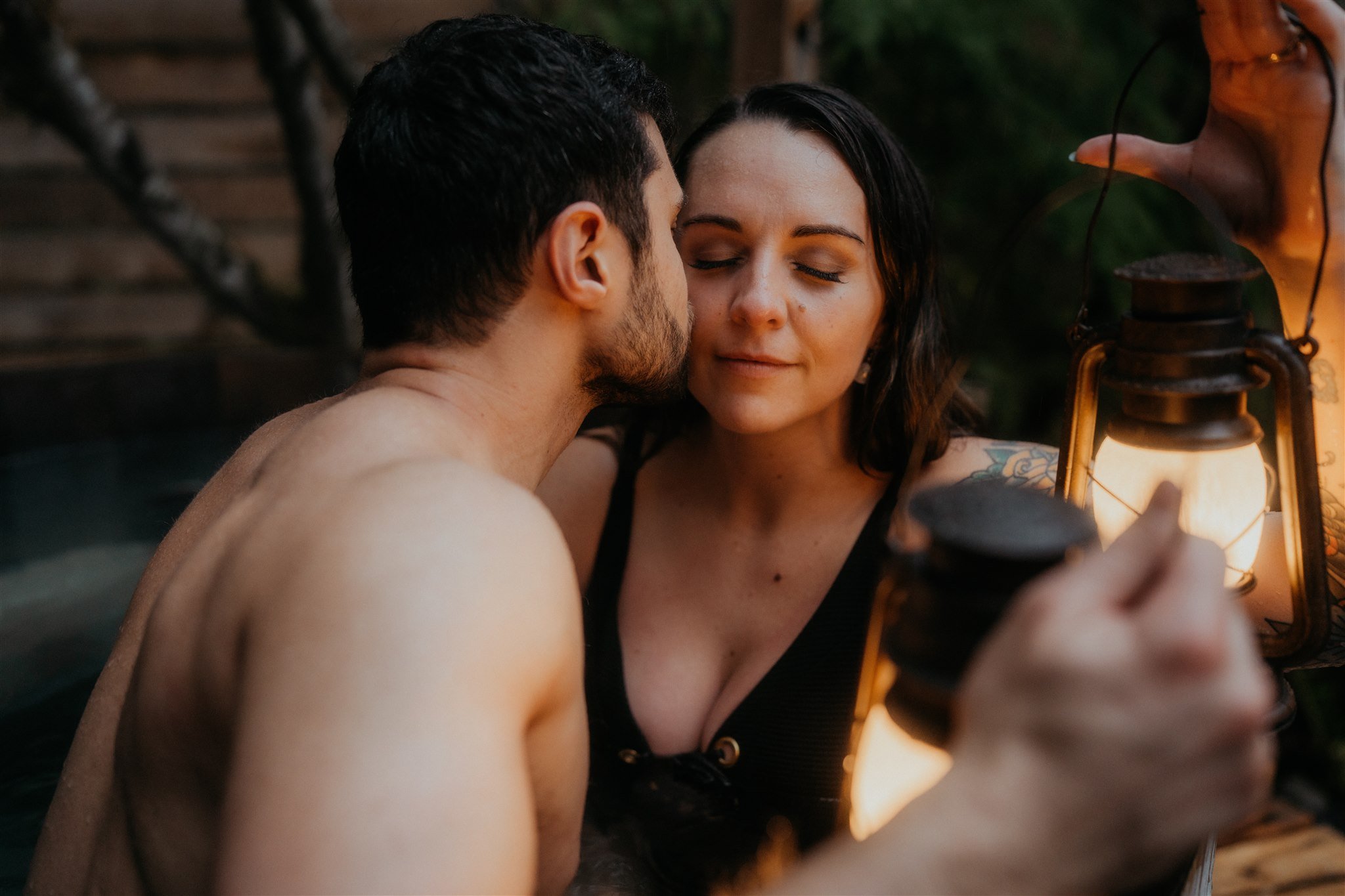Bride and groom kiss in barrel hot tub after snowy hiking elopement