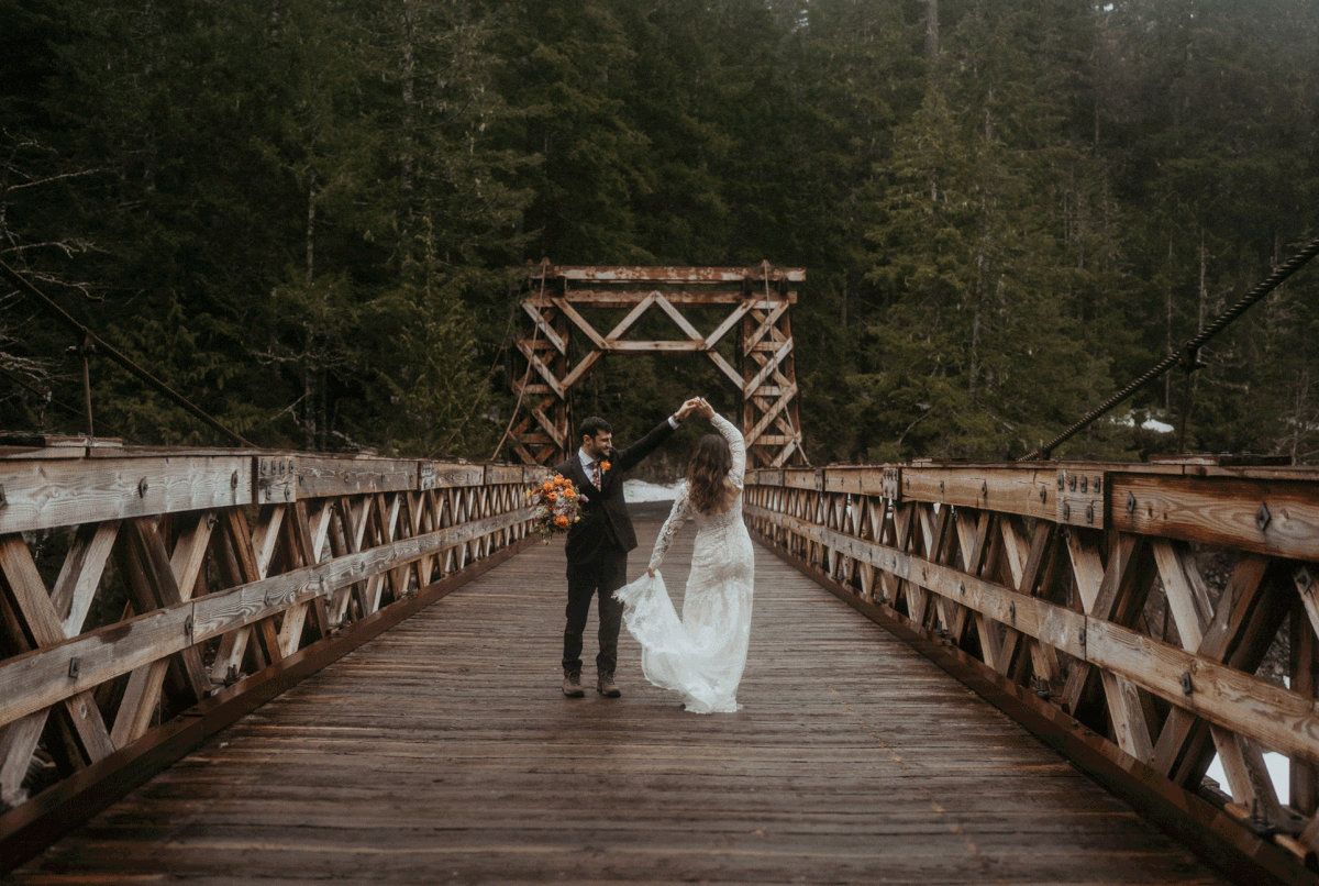 Bride and groom dancing on a bridge near Mt Rainier for their snowy mountain elopement