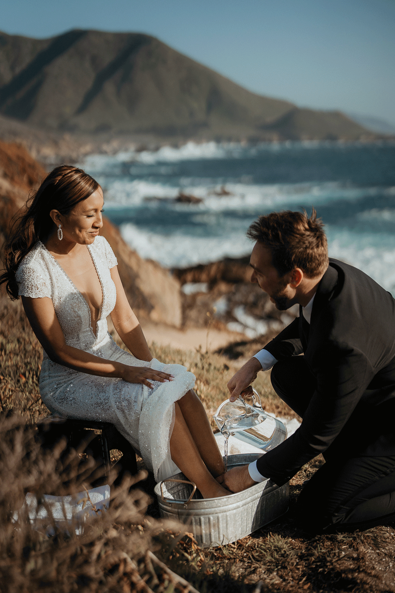 Groom washes bride's feet during wedding ceremony at Big Sur
