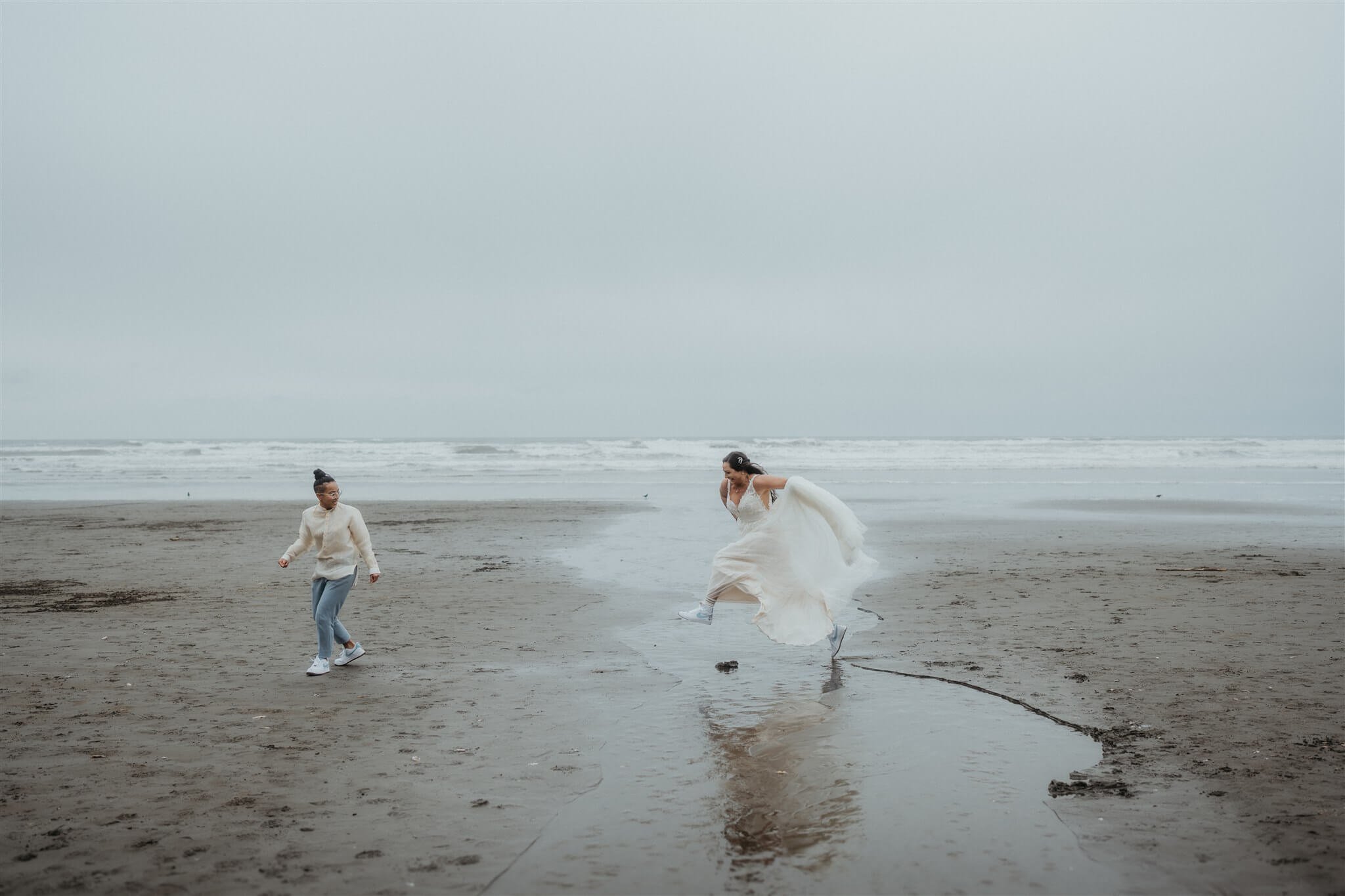 Two brides jump across water stream at Ruby Beach elopement