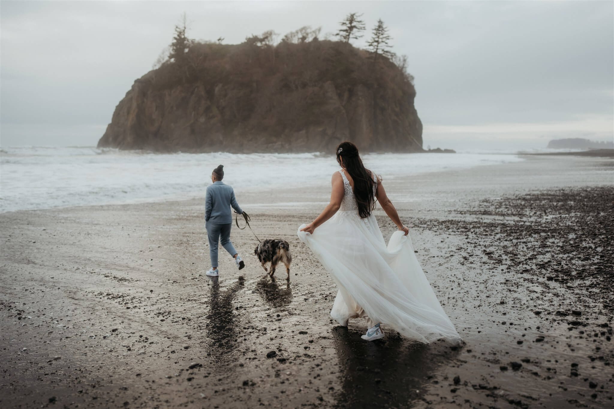Brides walking with their dog along Ruby Beach at sunset