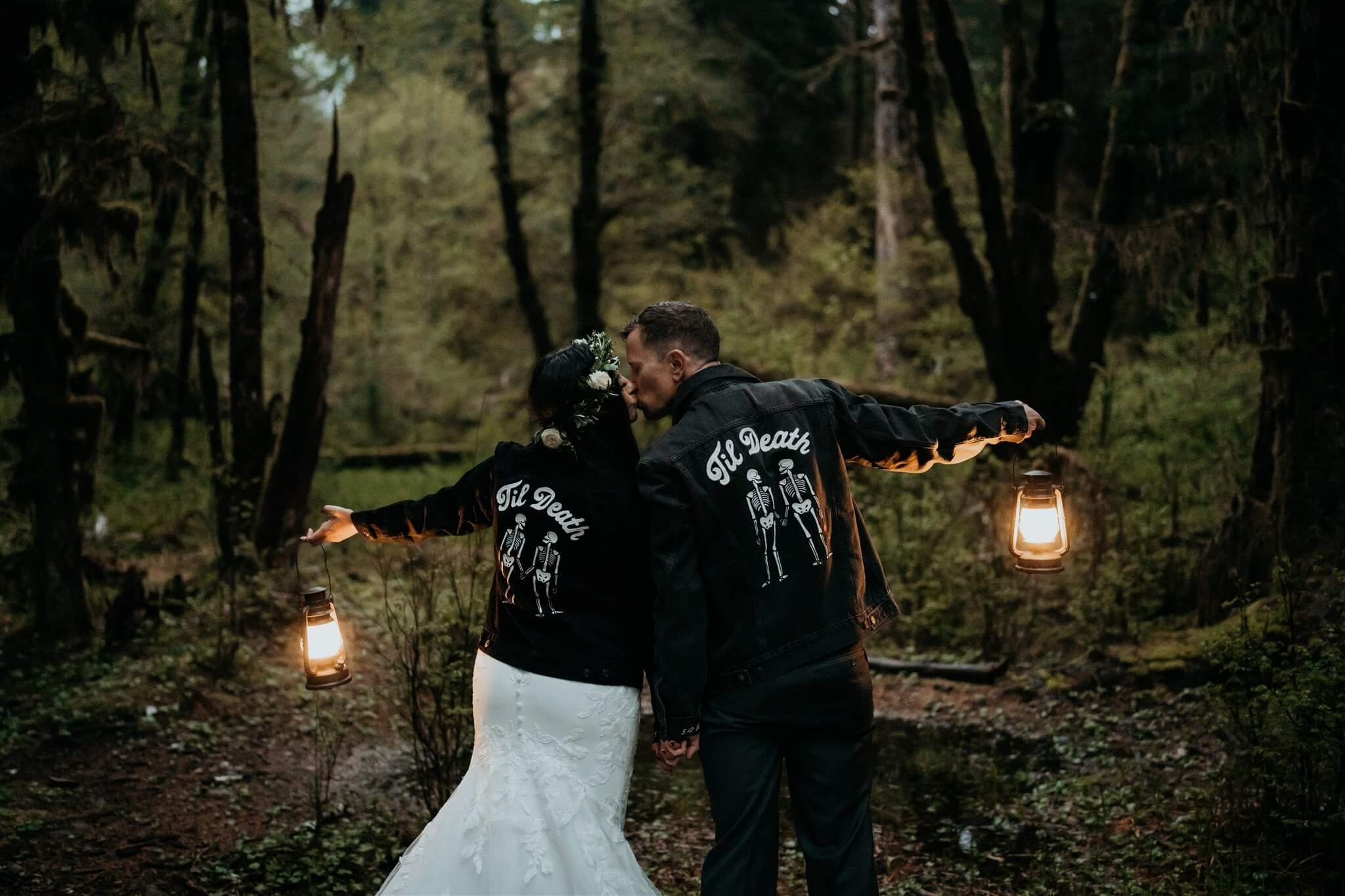 Bride and groom holding lanterns in the forest 