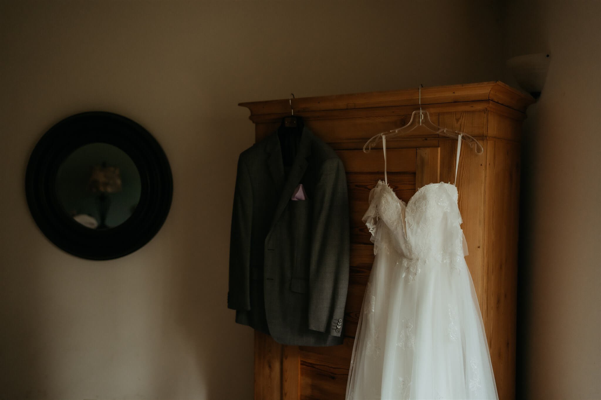 Wedding dress and suit hanging on an armoire  