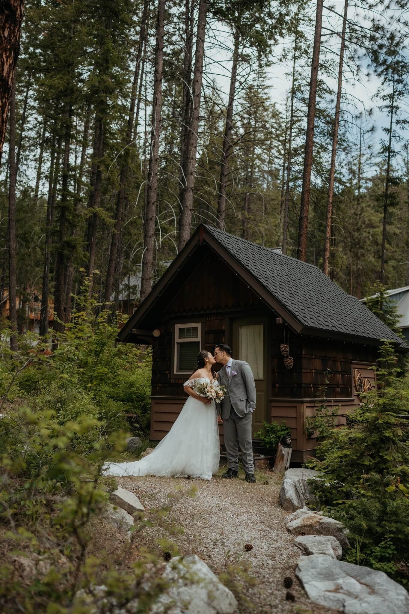 Bride and groom kiss in front of cabin in the North Cascades forest