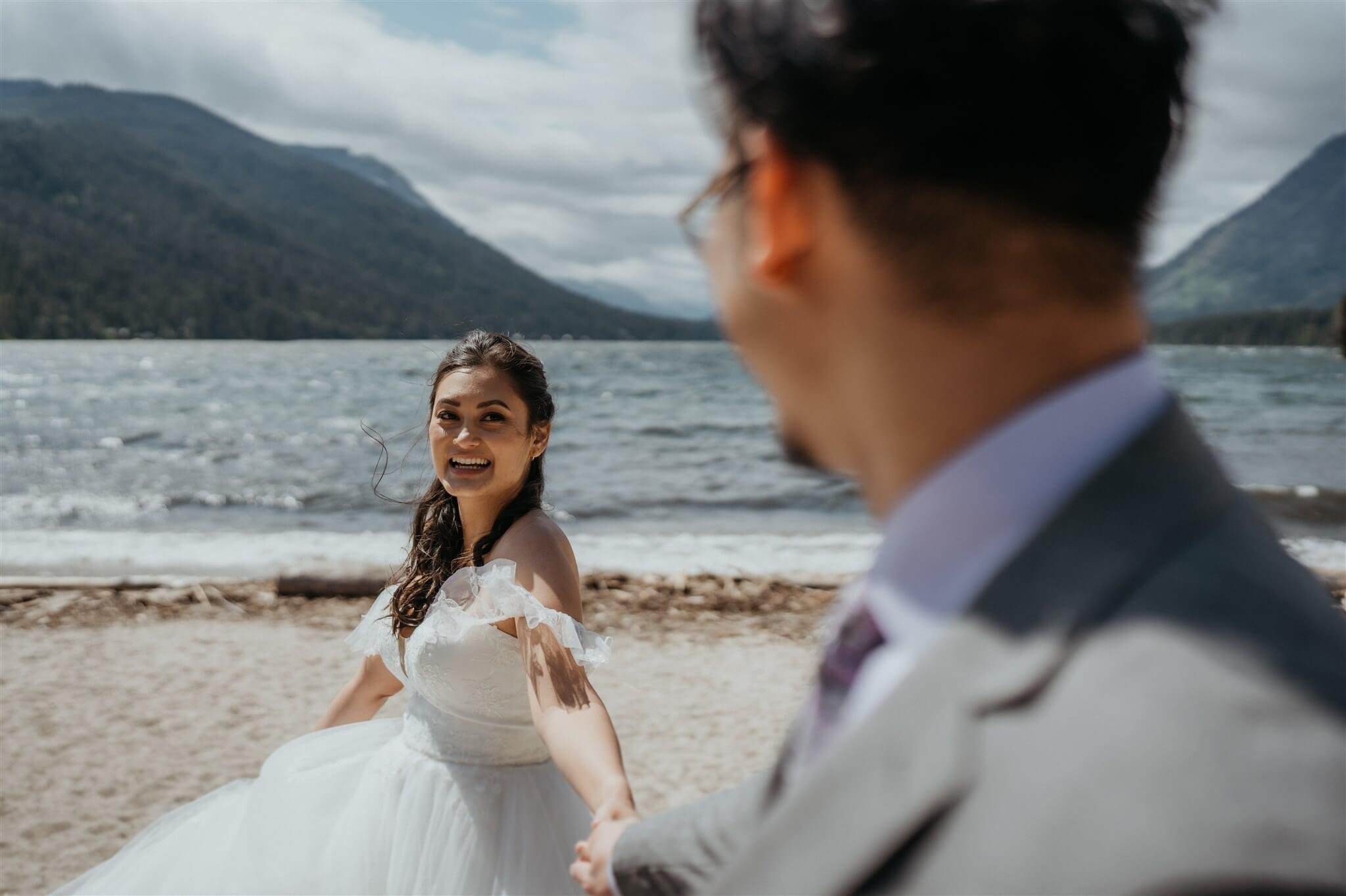 Bride and groom hold hands while walking along Barclay Lake