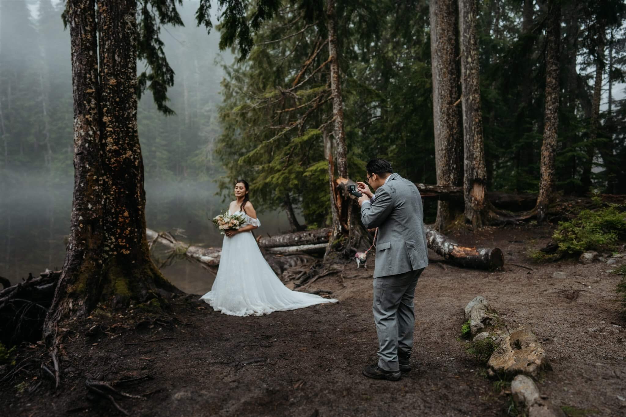 Groom takes photo of bride in the forest