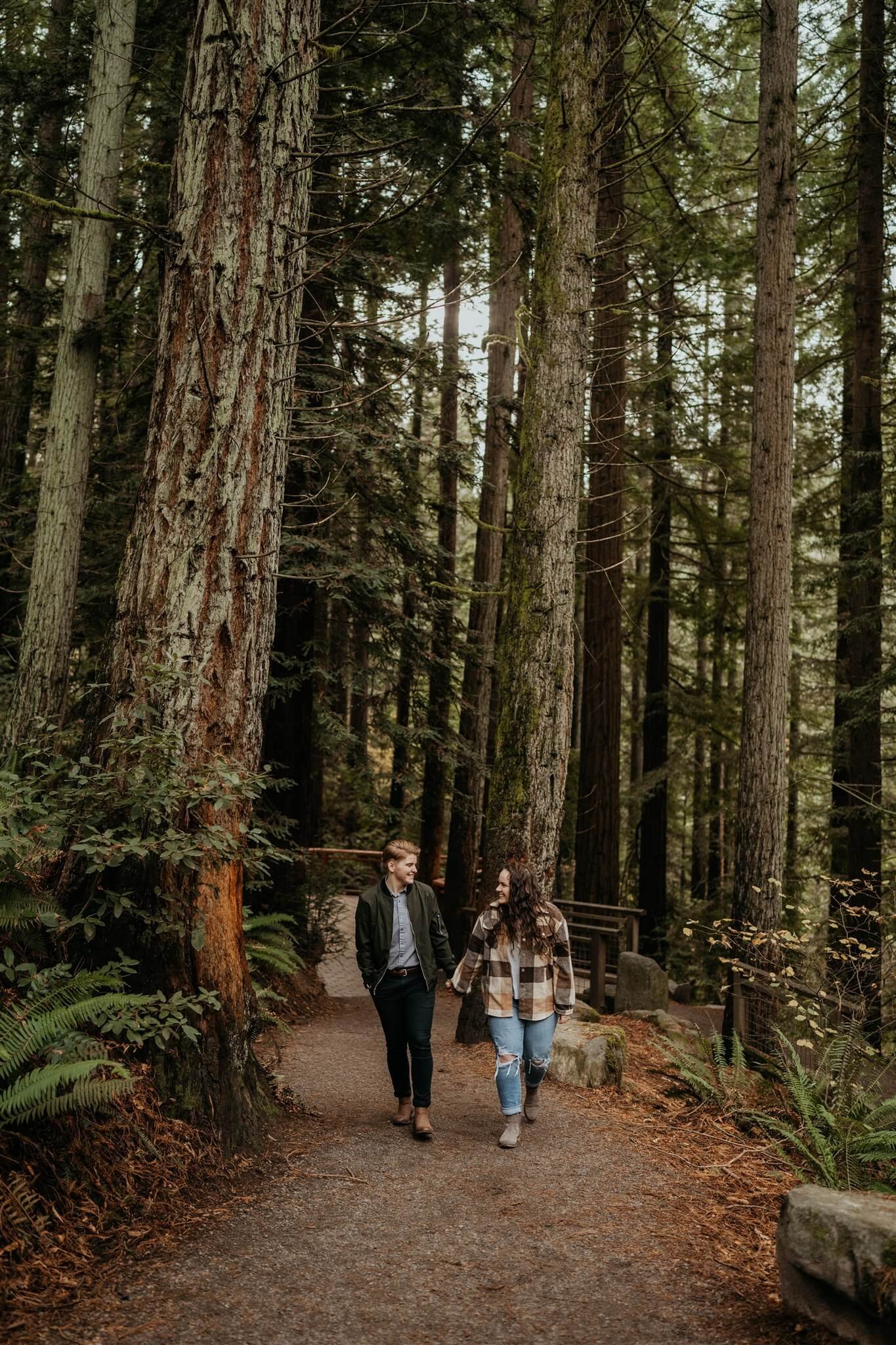 LGBT couple holding hands while walking through the forest